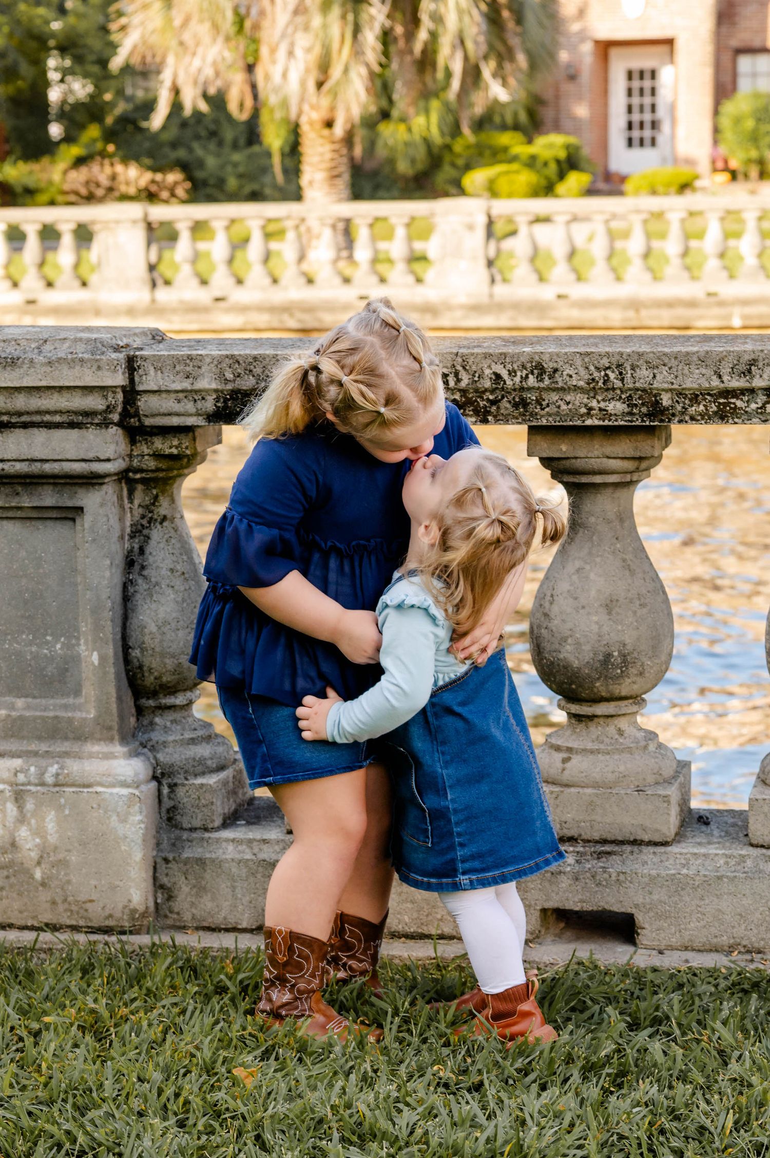 Two people share an intimate moment while sitting on stone steps in a garden setting at sunset.