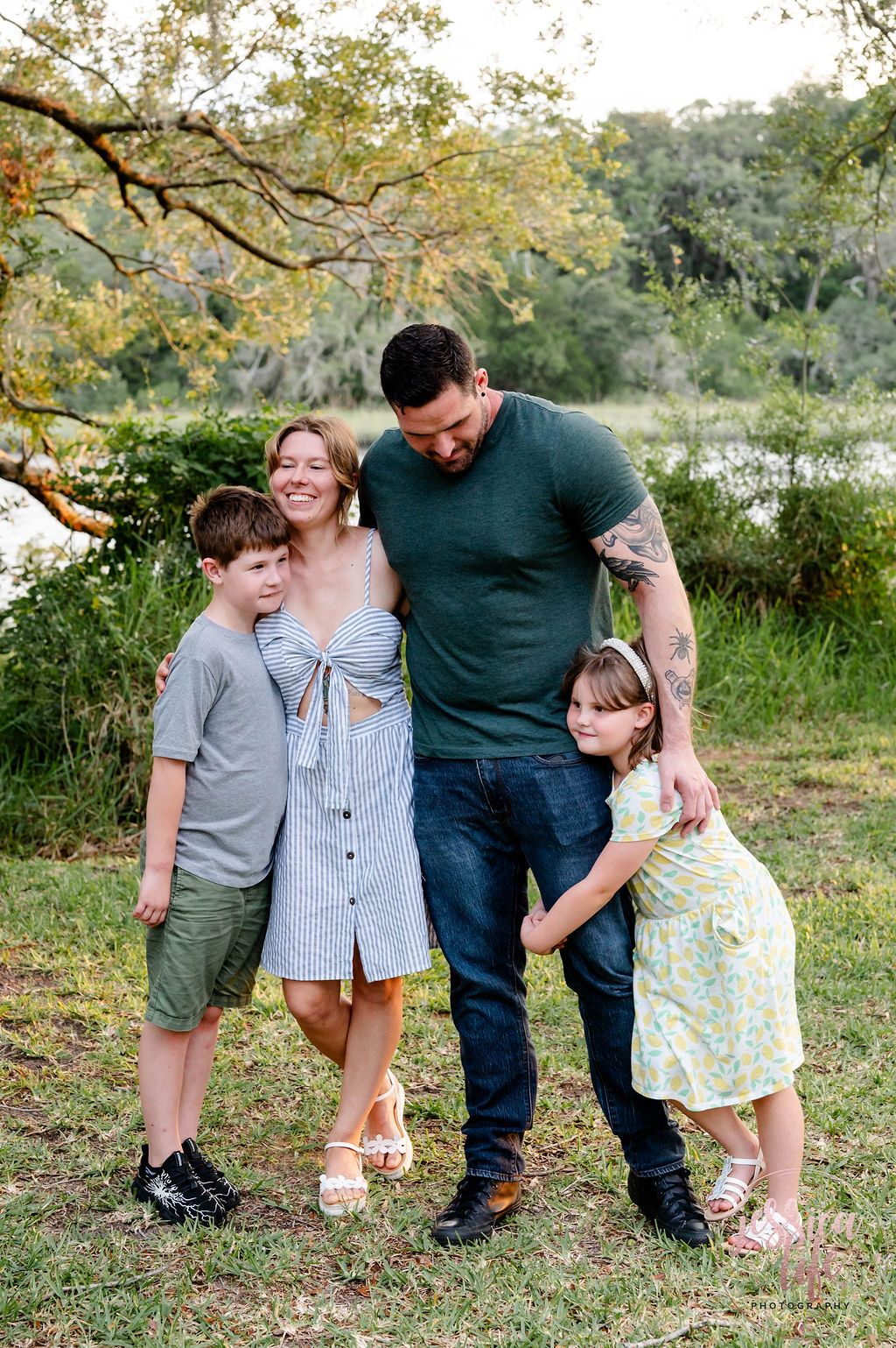 Family of four shares tender moment together in outdoor nature setting.