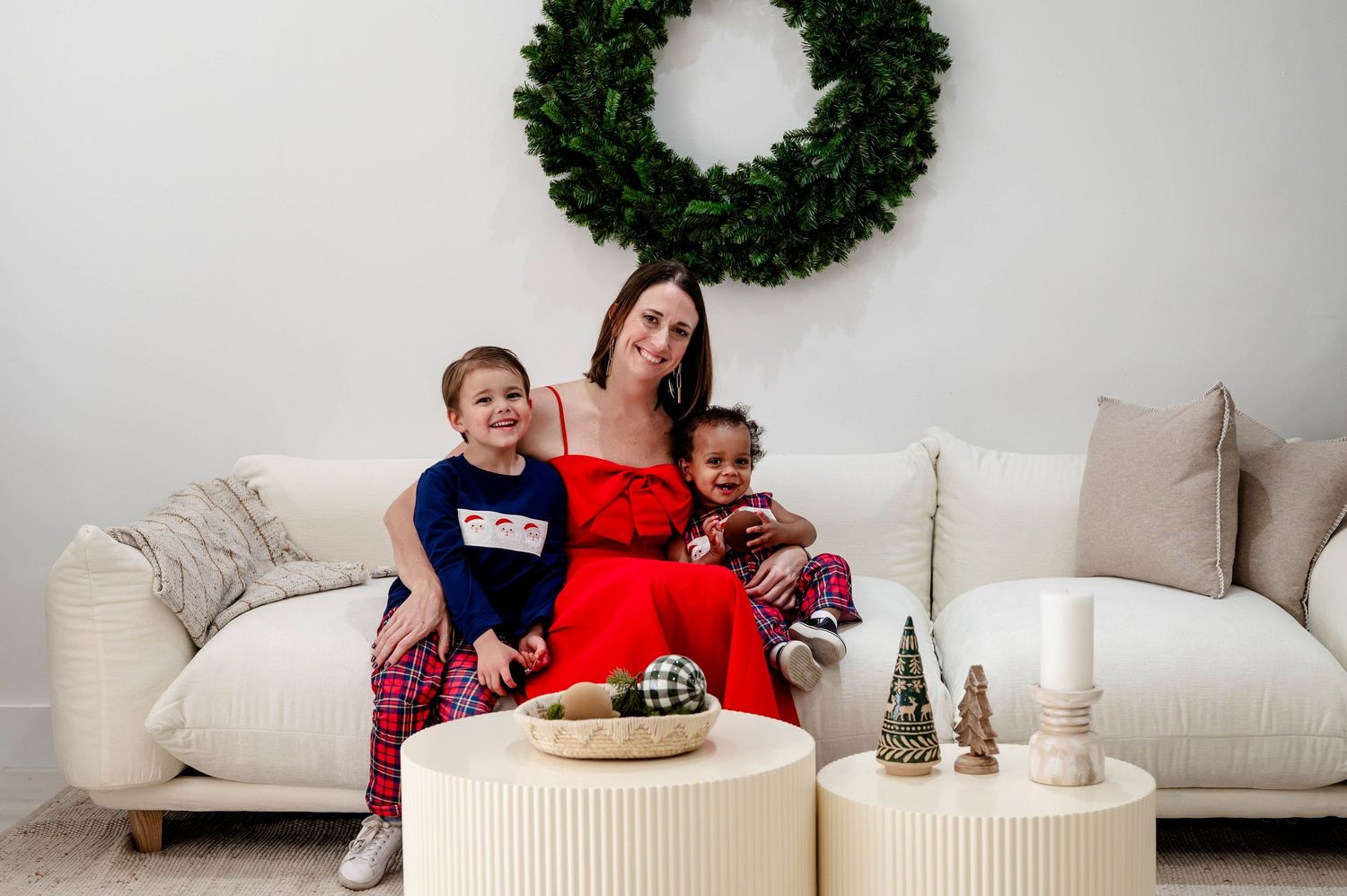 Family gathering in festive red and white outfits around a modern ottoman during Christmas celebrations.