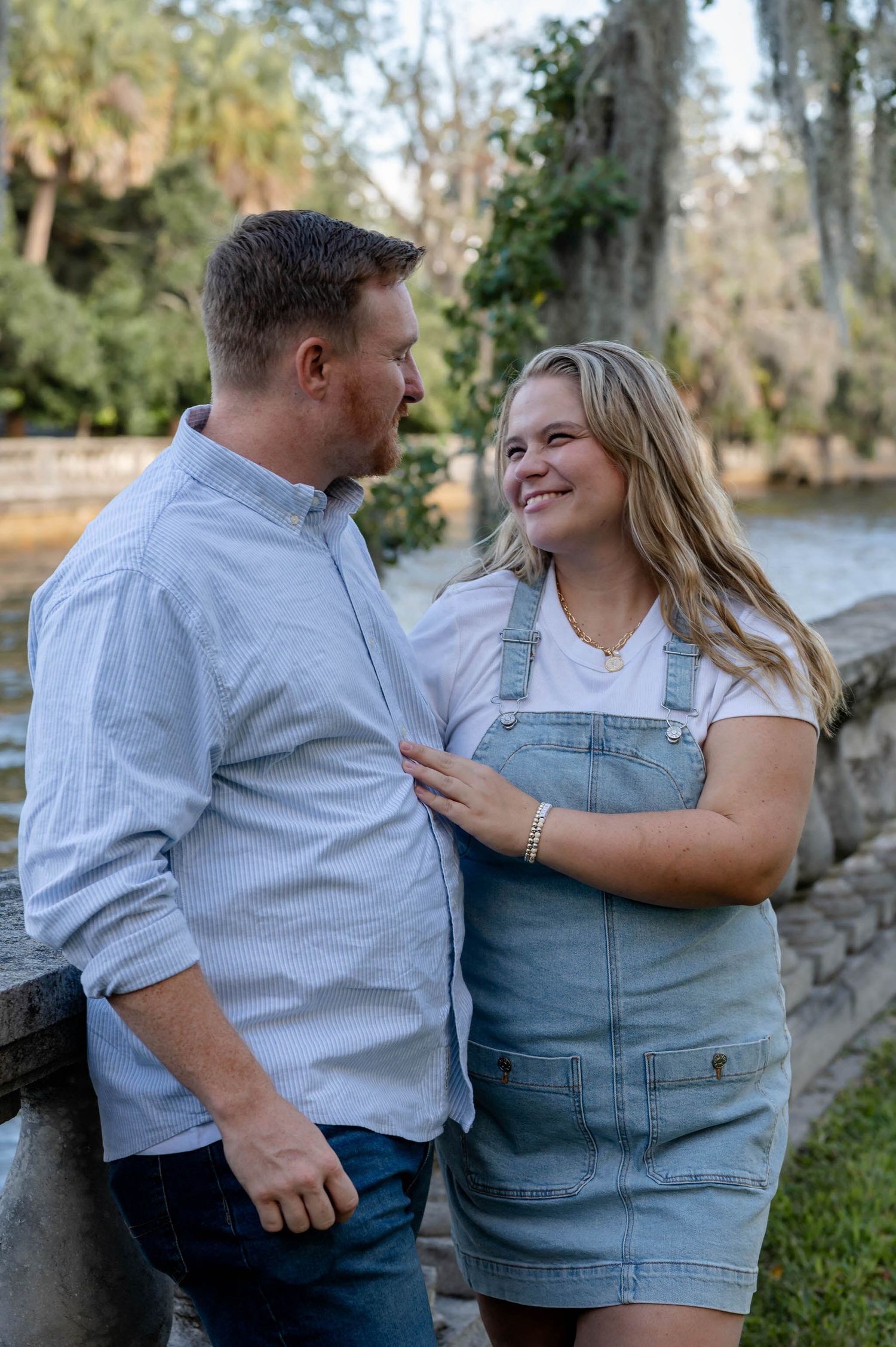 A couple in casual attire shares intimate moments by a lake, captured in a series of candid romantic poses.