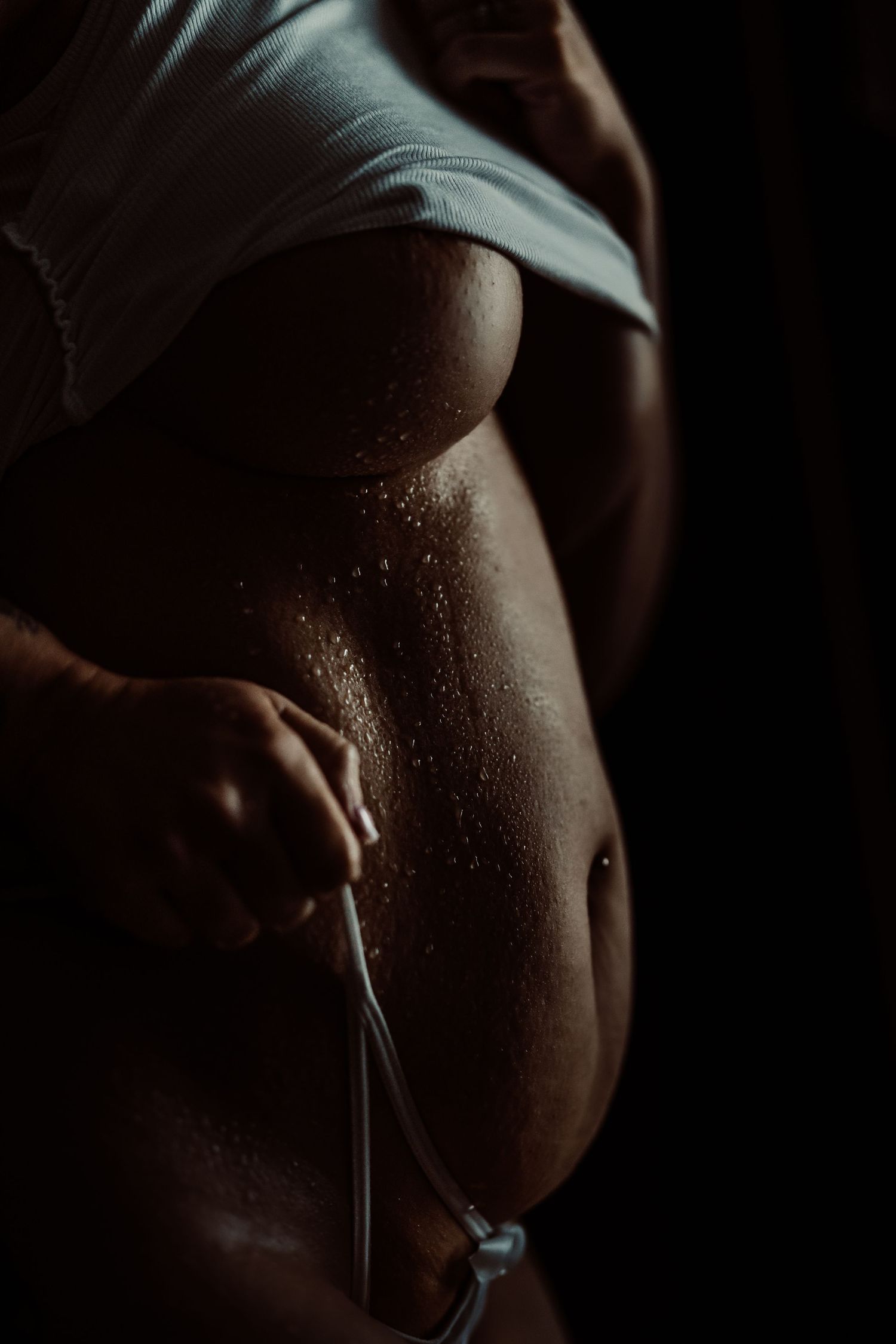 Close-up artistic photo series showing water droplets on dark skin in dramatic lighting.