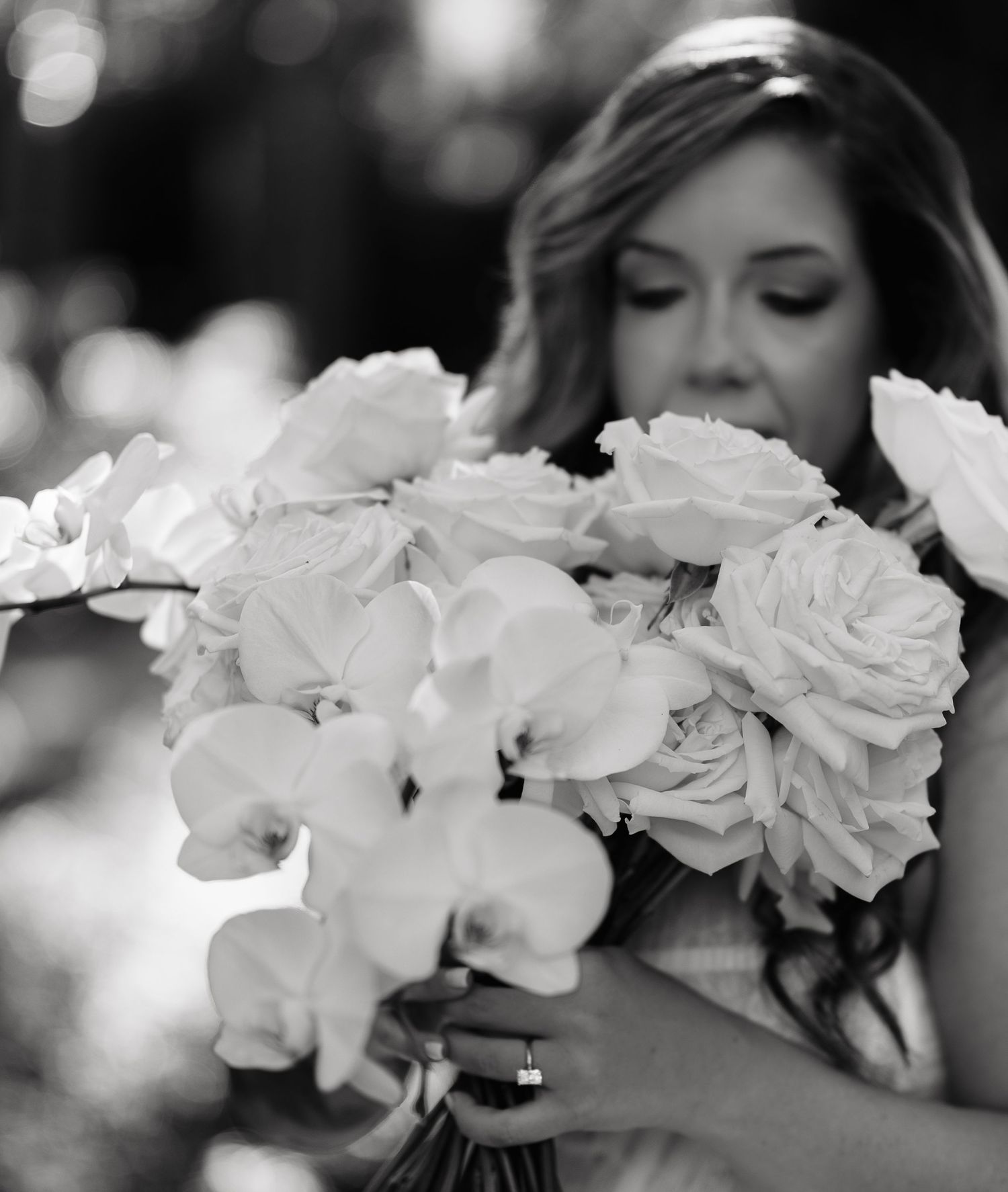 A close-up black and white photograph of delicate white roses with soft bokeh effect in the background.