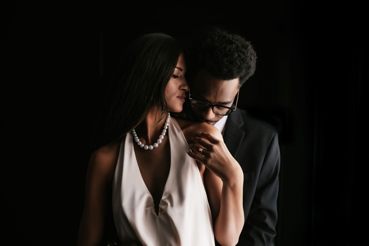 A romantic couple in formal attire embraces intimately during what appears to be a wedding photo session.
