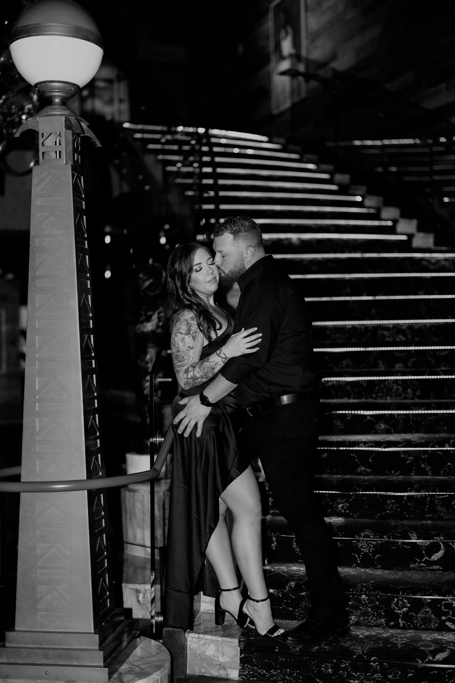 Dramatic black and white portrait session on stone steps with moody lighting and architectural elements.