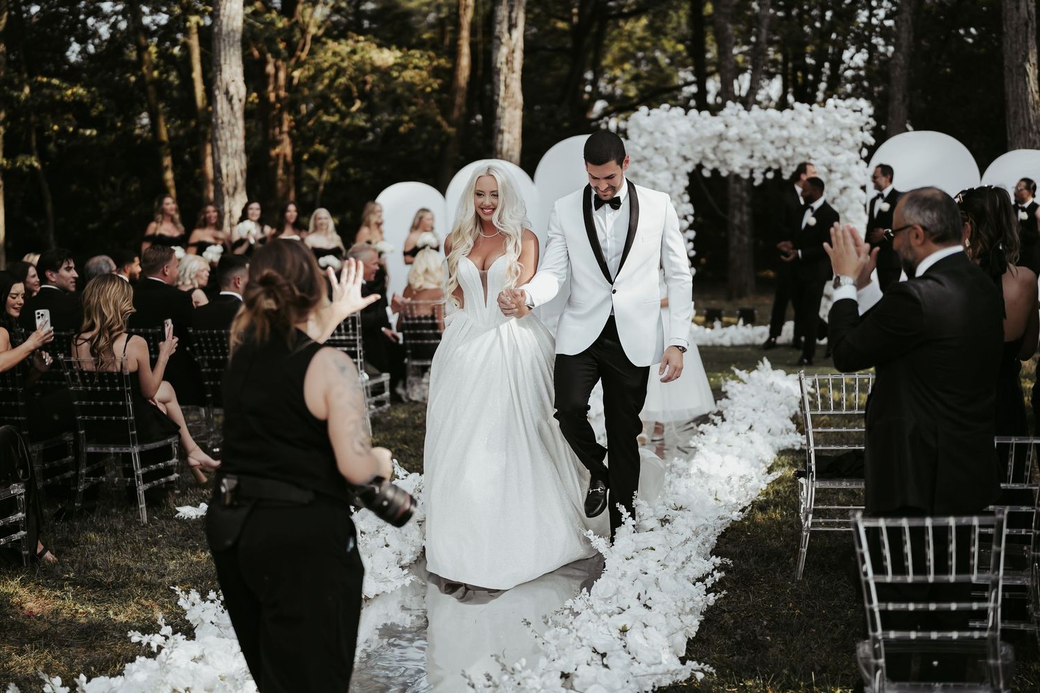 A joyful wedding celebration outdoors with guests watching as the couple shares their first dance under string lights.