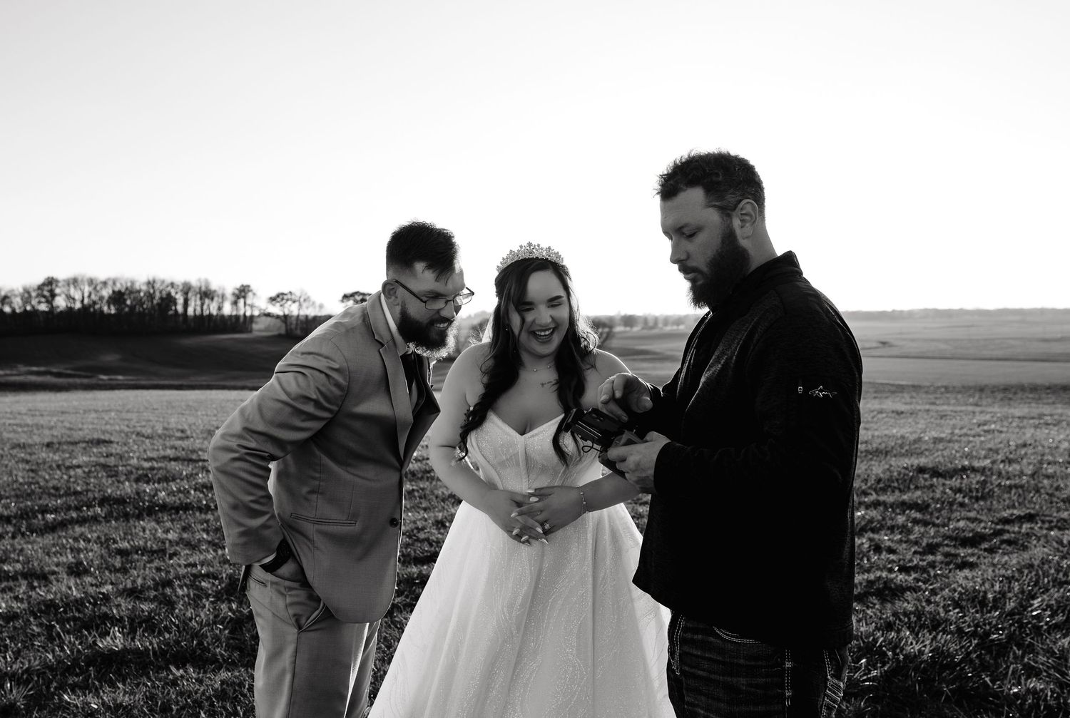A series of black and white wedding photos showing romantic moments between a couple in an outdoor field setting.