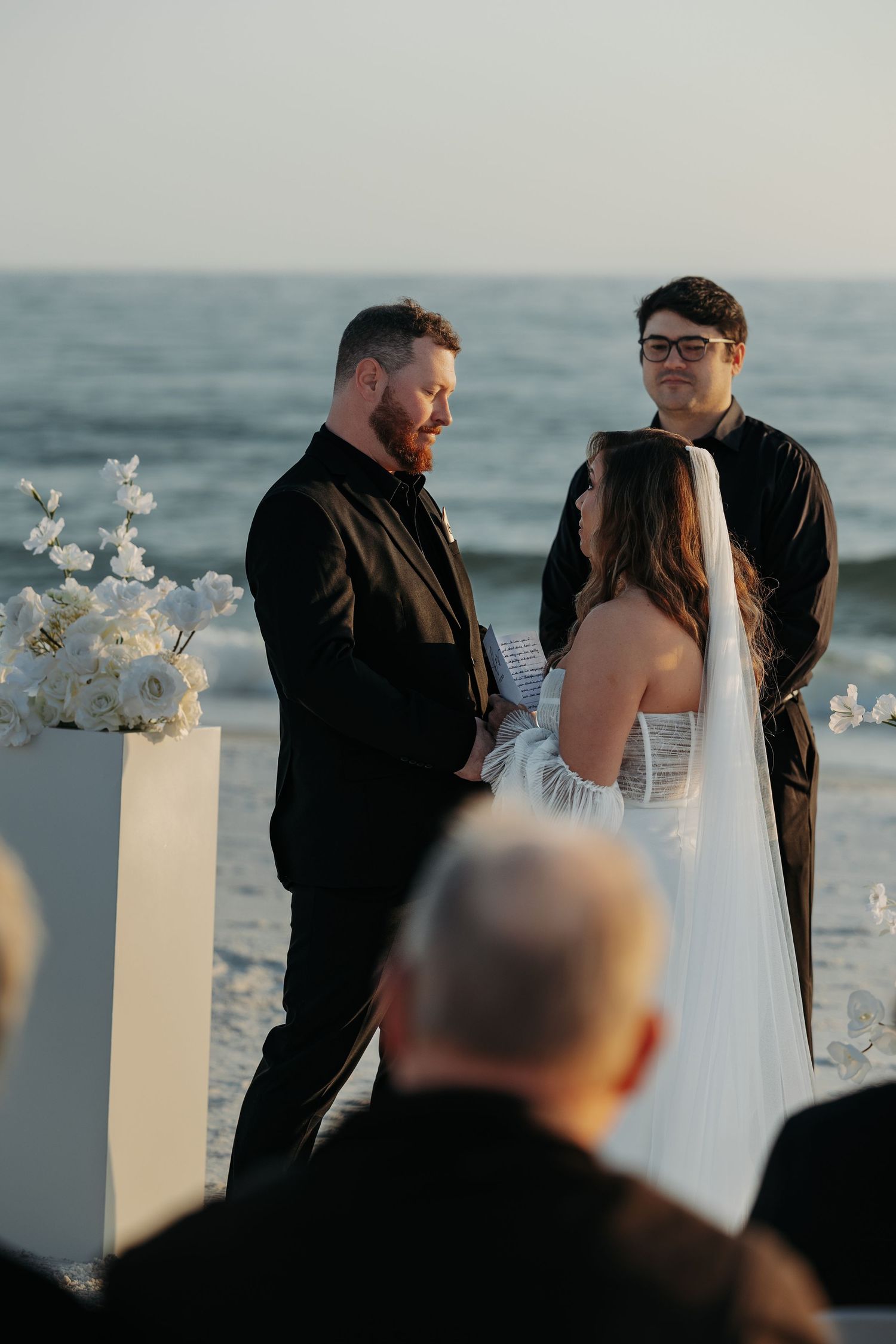 A beach wedding ceremony sequence showing the couple and officiant against an ocean backdrop at sunset.