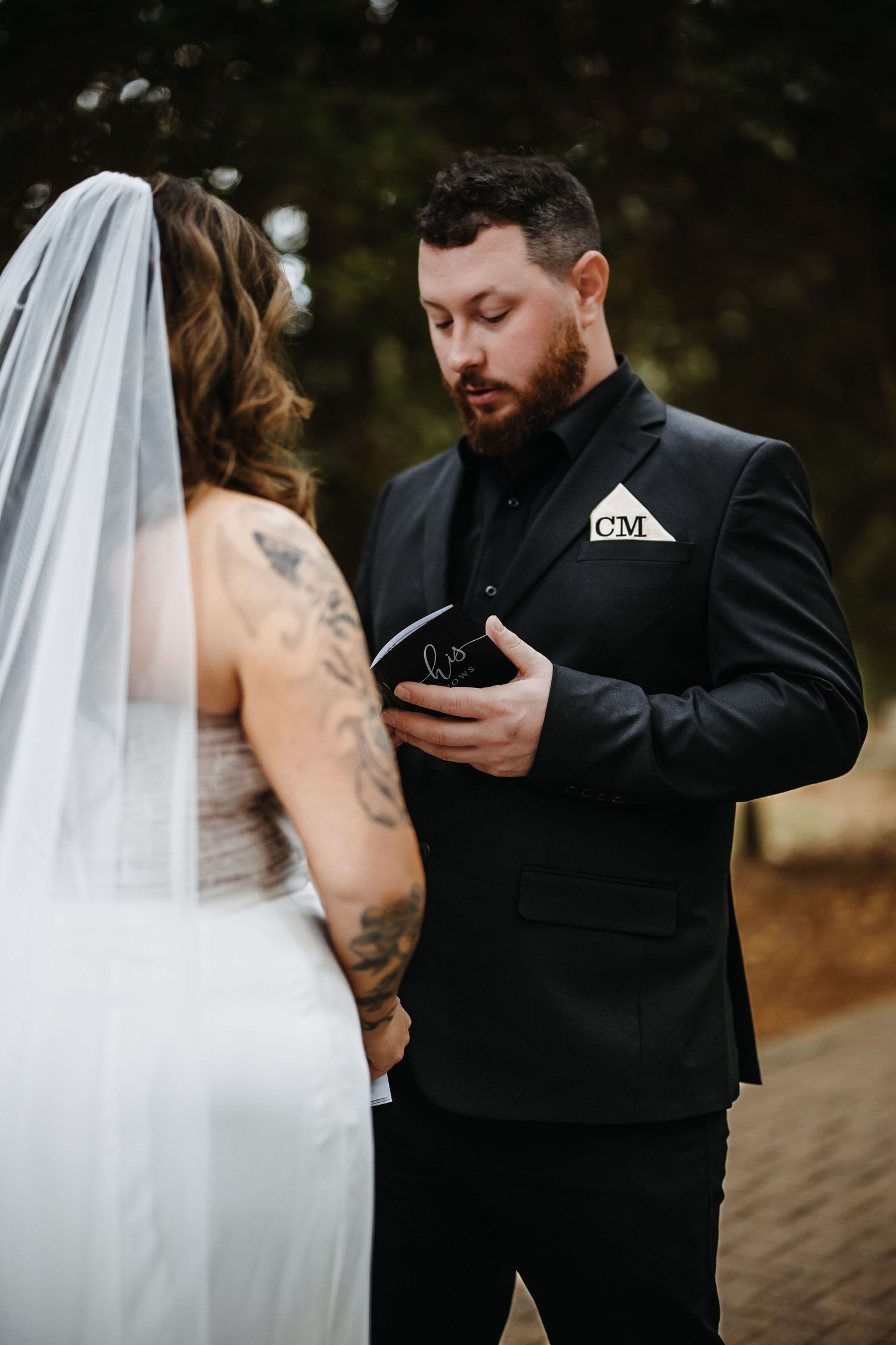 A romantic first look moment between a bride in white and groom in black during an outdoor wedding ceremony.