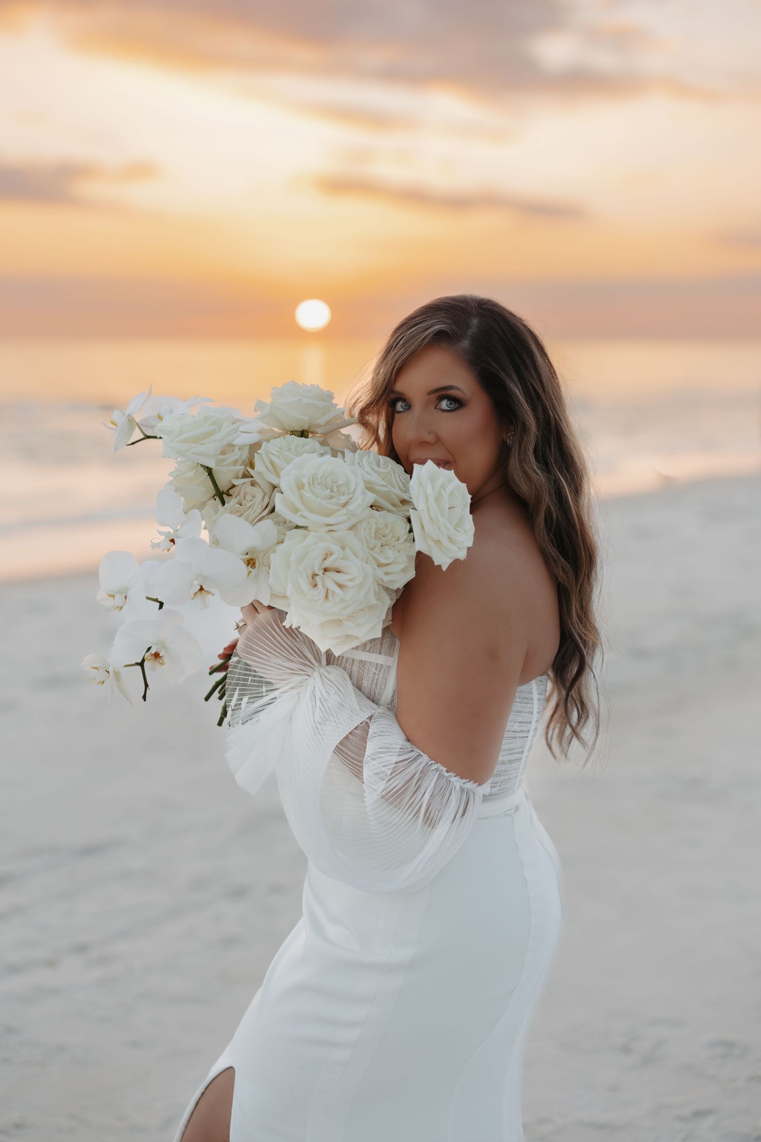 A figure in a white wedding dress holds a bouquet of white orchids on a sandy beach at sunset.
Cheeca Lodge & Spa
