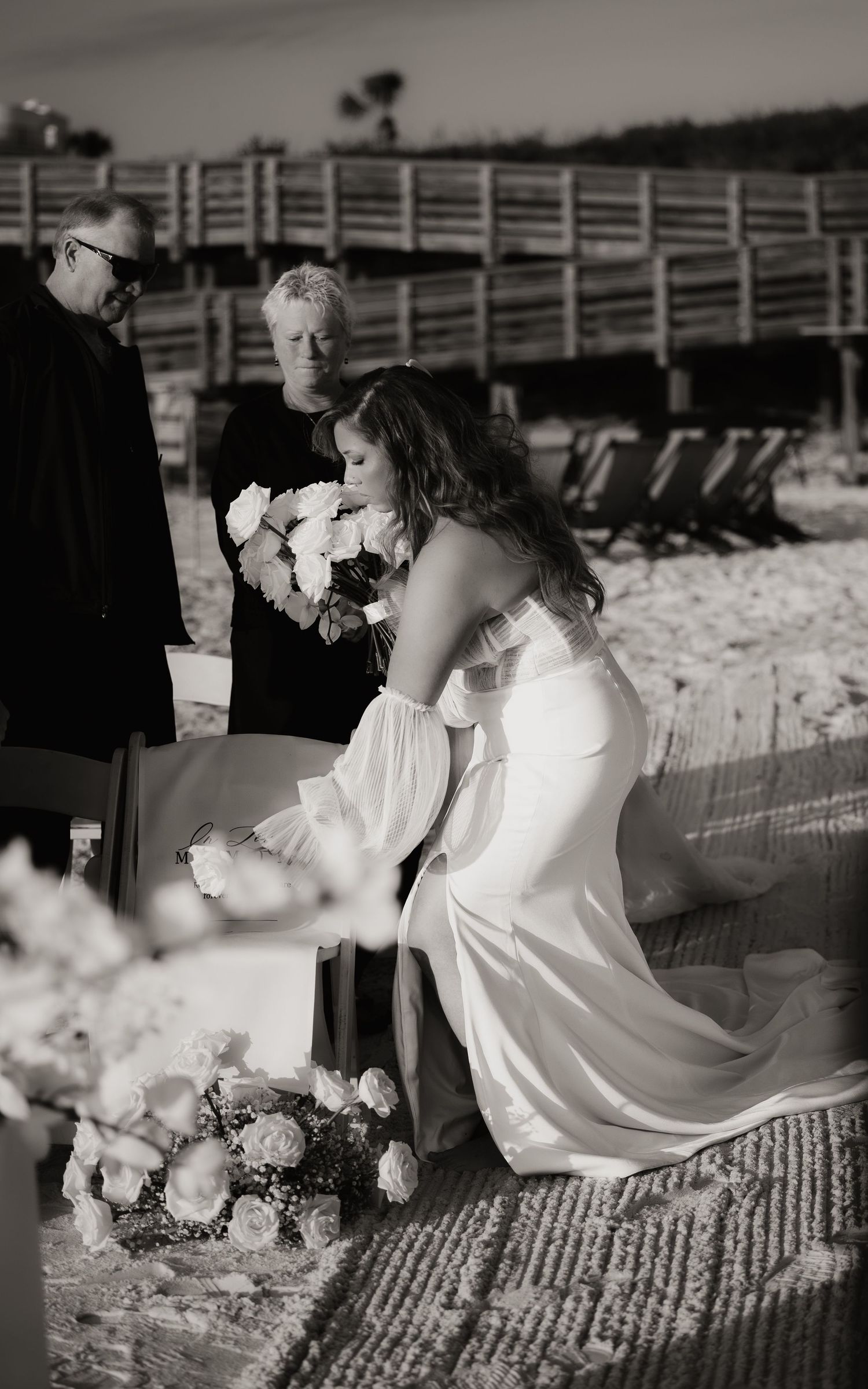 A romantic black and white photo series showing a couple in wedding attire sitting together on a rustic wooden fence.