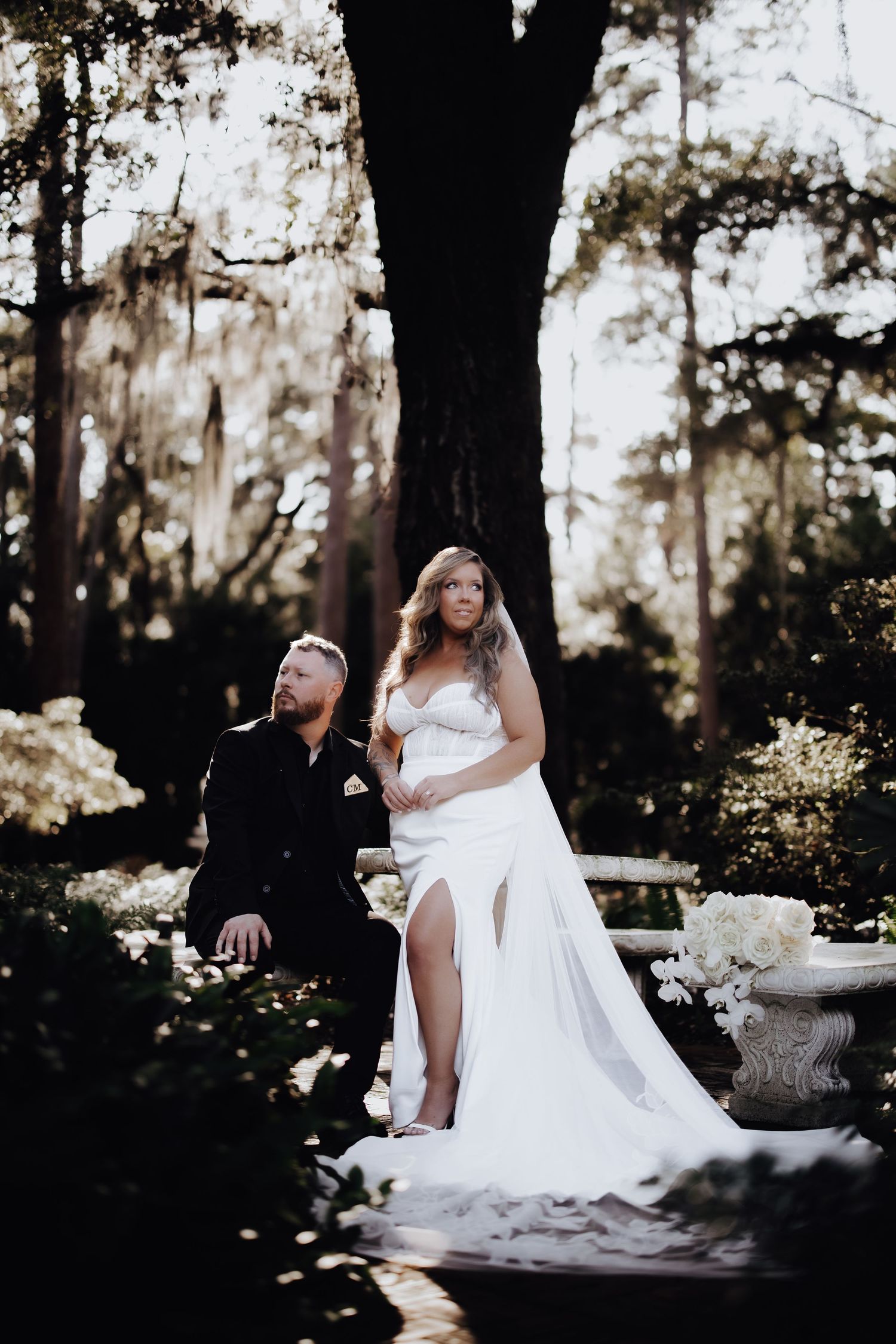 A couple in wedding attire poses dramatically under a large tree in a moody garden setting at sunset.
Mayfair House Hotel & Garden