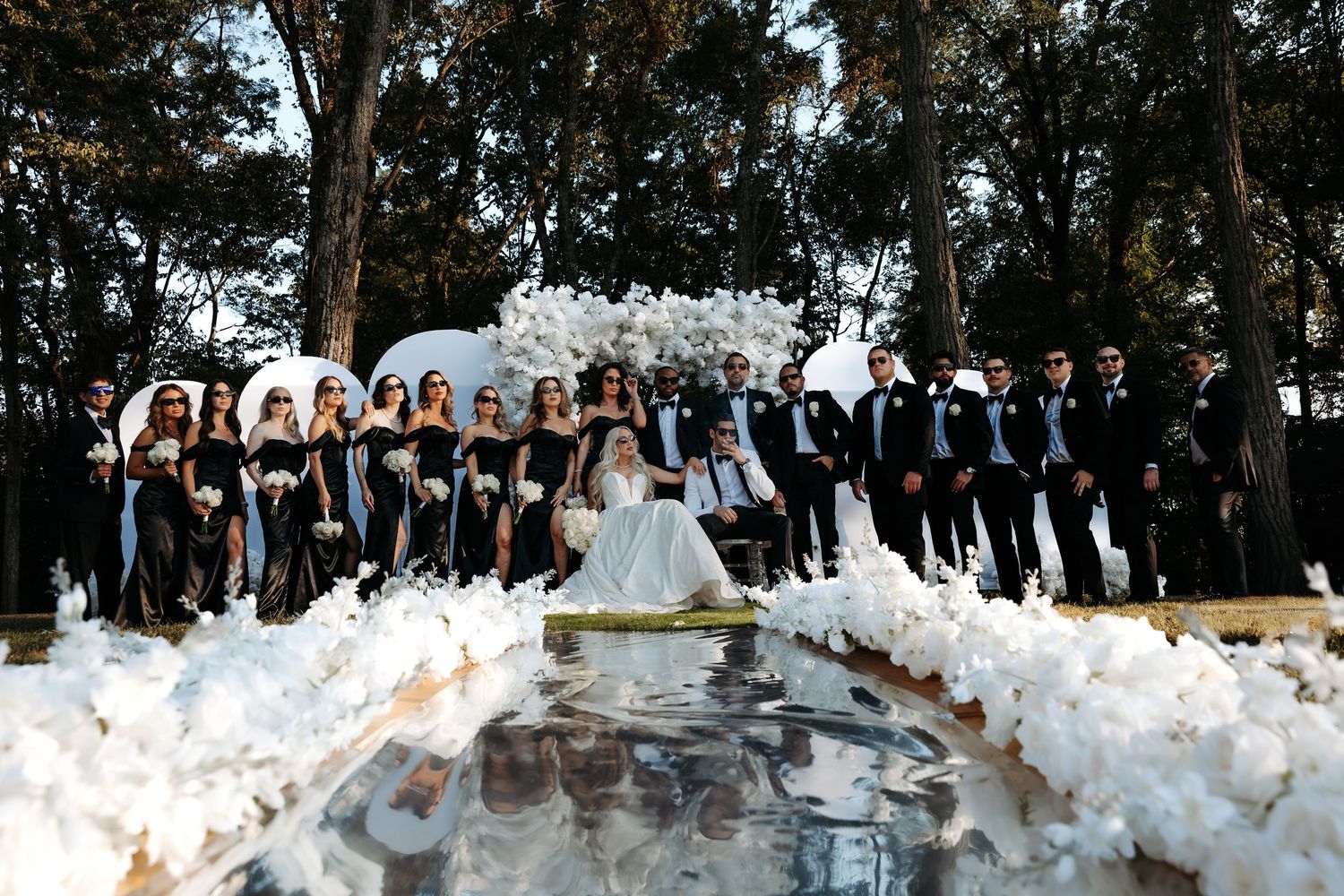 A large crowd gathers outdoors in a wooded area for what appears to be a festive celebration or event.