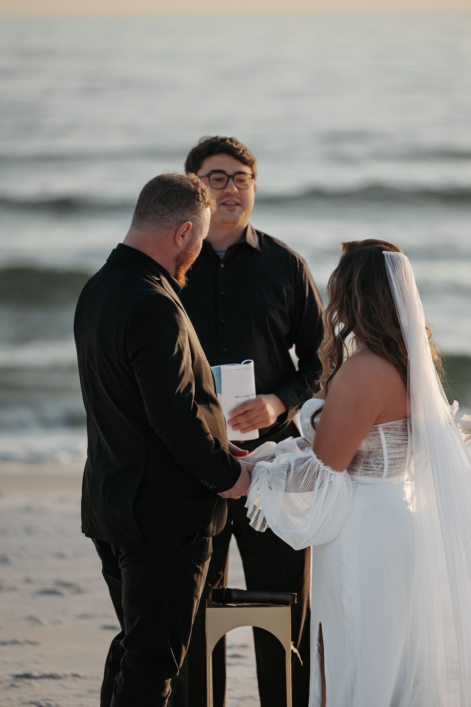A beach wedding ceremony unfolds in a series of intimate moments as a couple exchanges vows by the ocean.