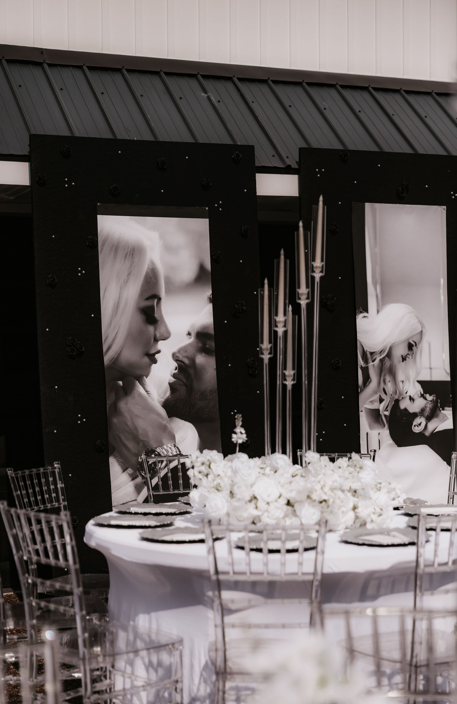 Elegant black and white wedding reception table setting with crystal glassware and white floral centerpieces.