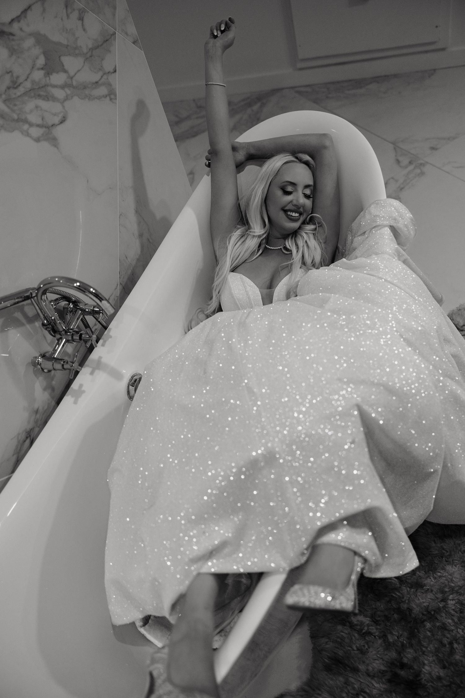 A person wearing a sparkly white wedding dress lies gracefully on a dark floor in a series of artistic poses.