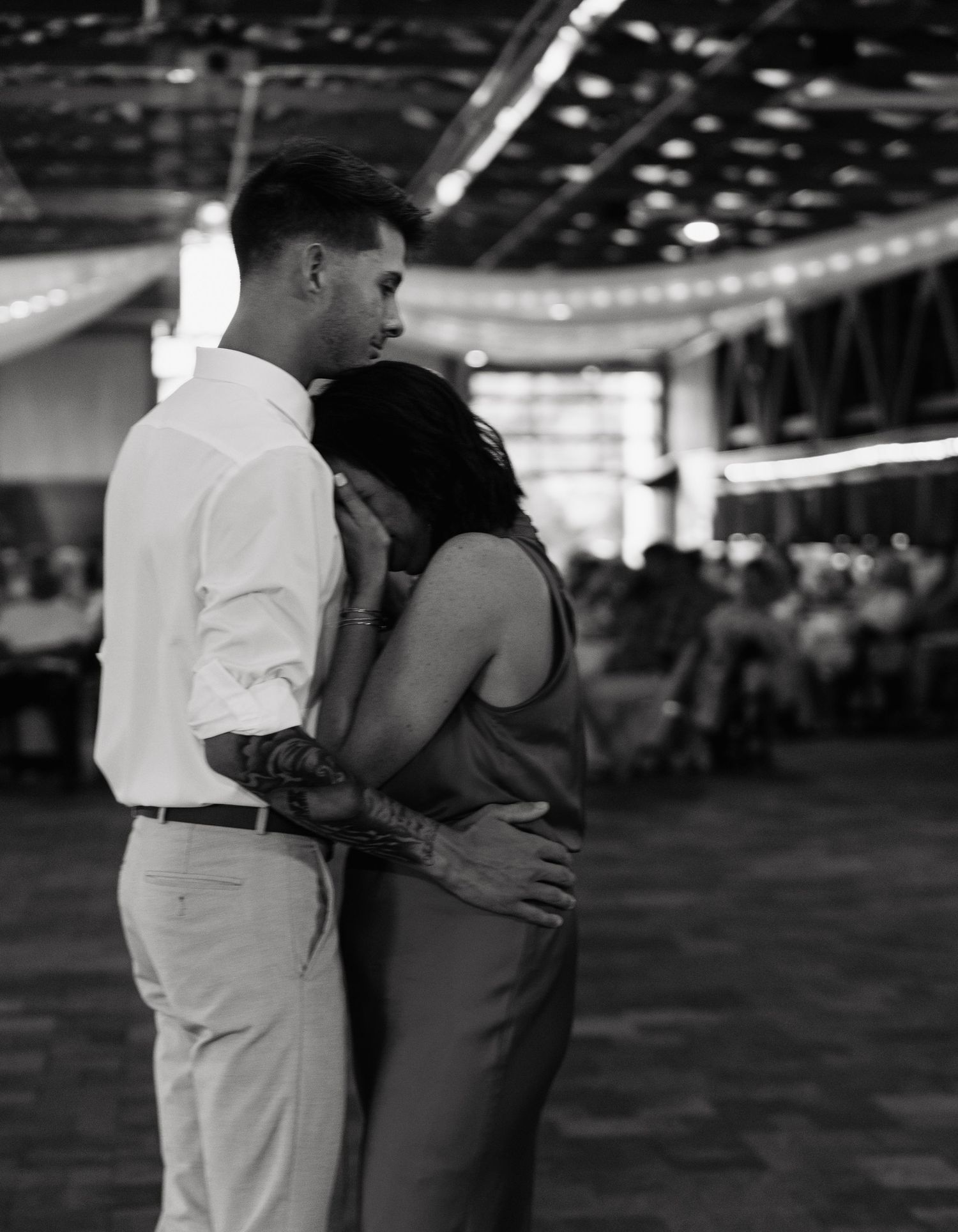 Couple shares intimate first dance embrace in black and white photo at elegant barn wedding reception.