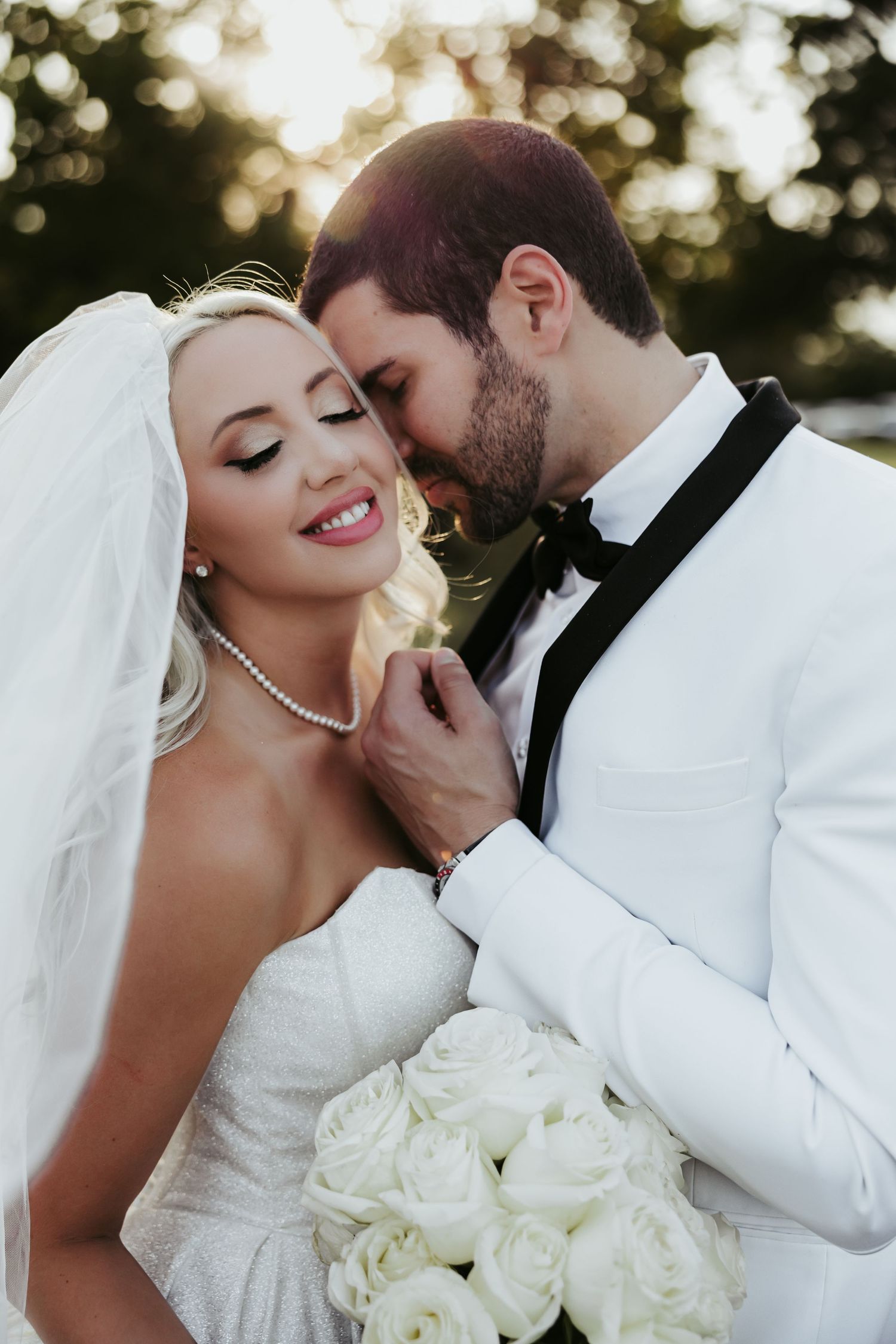 Intimate wedding photos capturing romantic moments between bride and groom with white roses and pearl necklace details.