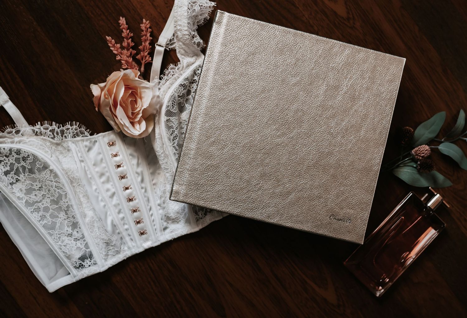 A vintage white lace wedding album with dried flowers and eucalyptus on dark wooden surface.
