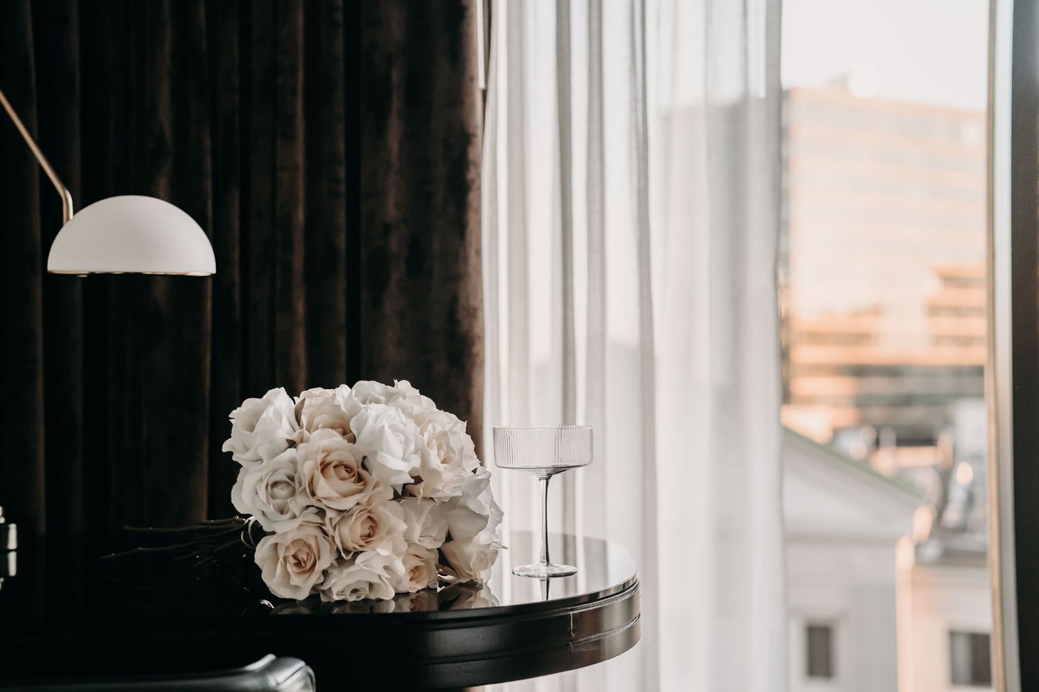 White orchids sit in a modern glass vase beside a window with natural light streaming in.