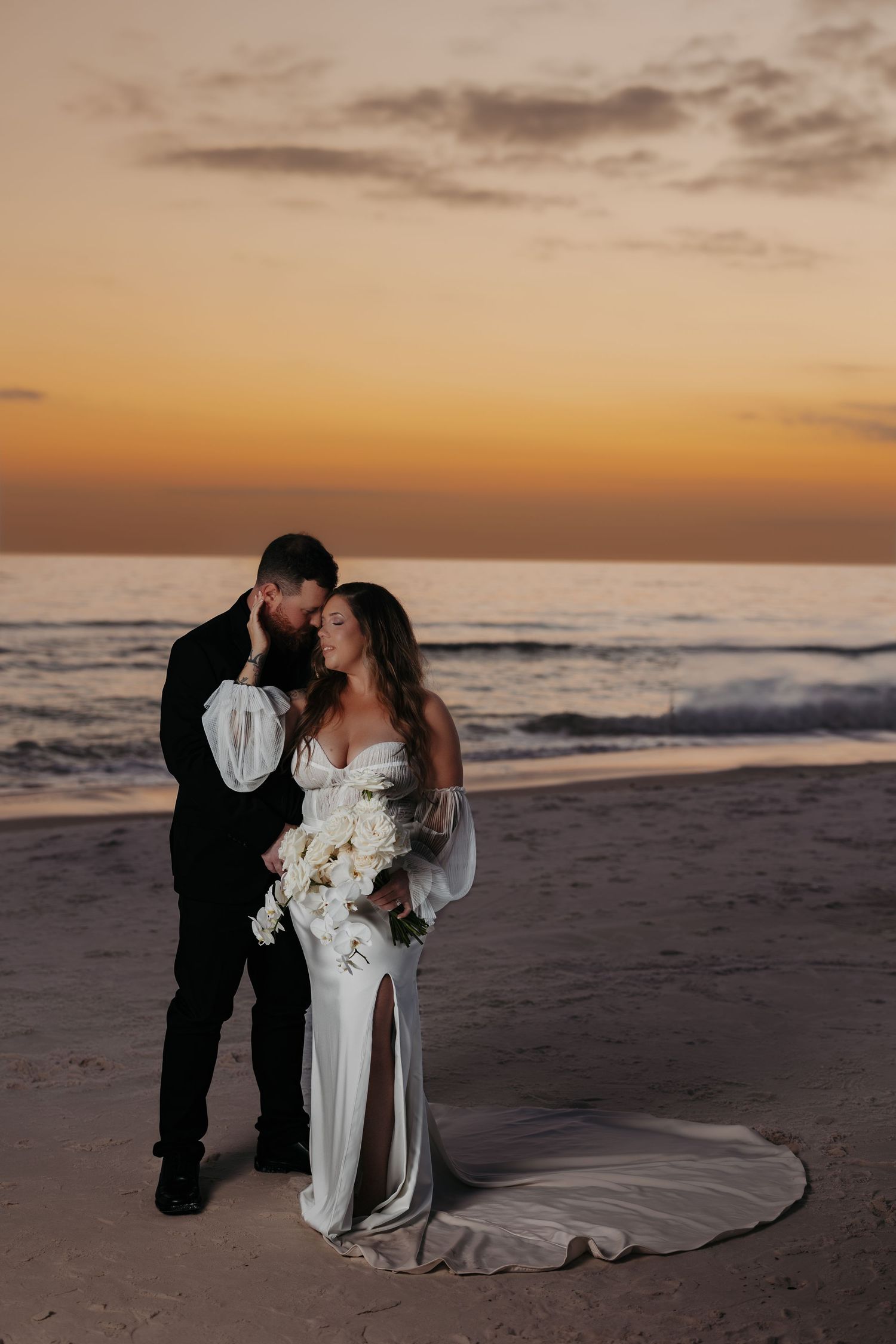 Romantic beach wedding photos at sunset with couple posing on sandy shore near ocean waves.