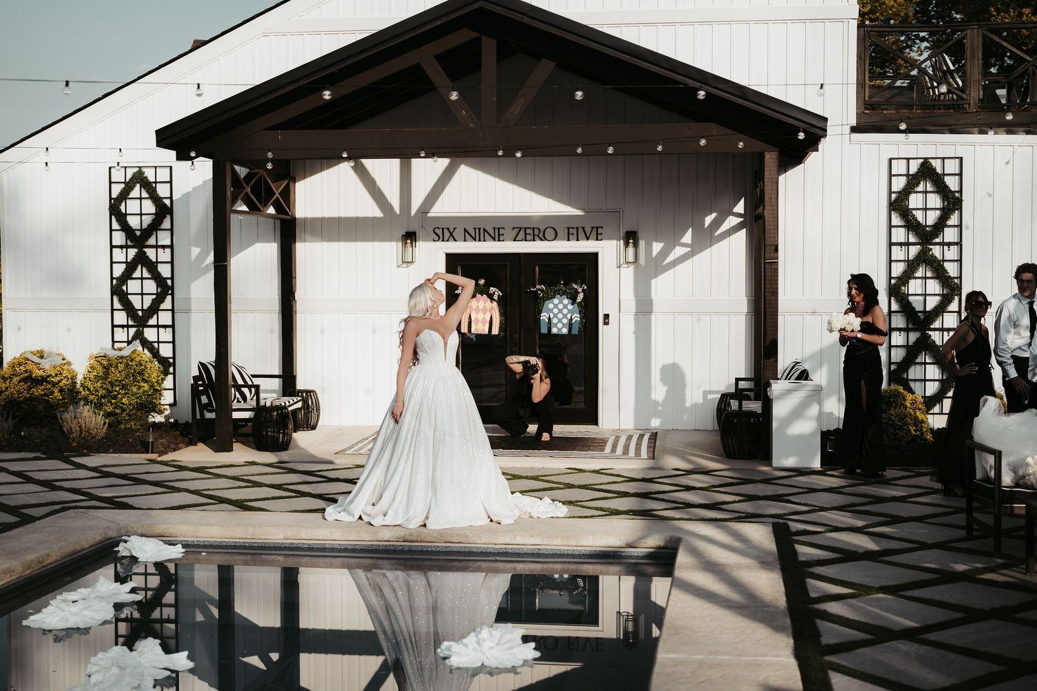 A couple poses in front of a rustic barn venue with string lights and wooden beams creating an elegant wedding atmosphere.
