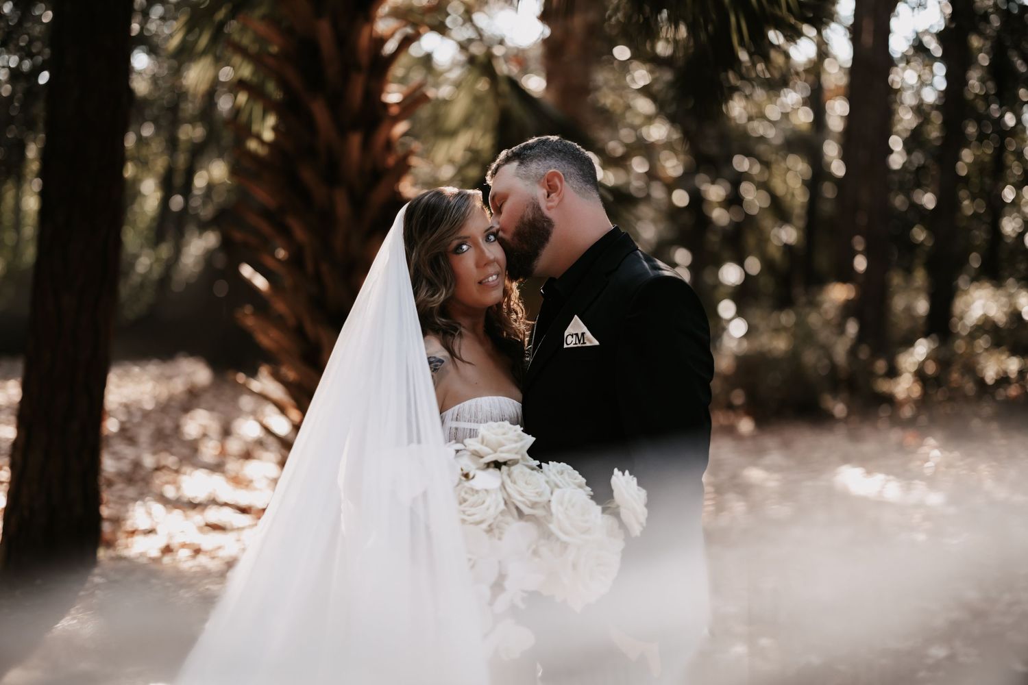 A romantic wedding couple shares an intimate moment in a sunlit forest setting with a flowing white veil.
Mayfair House Hotel & Garden