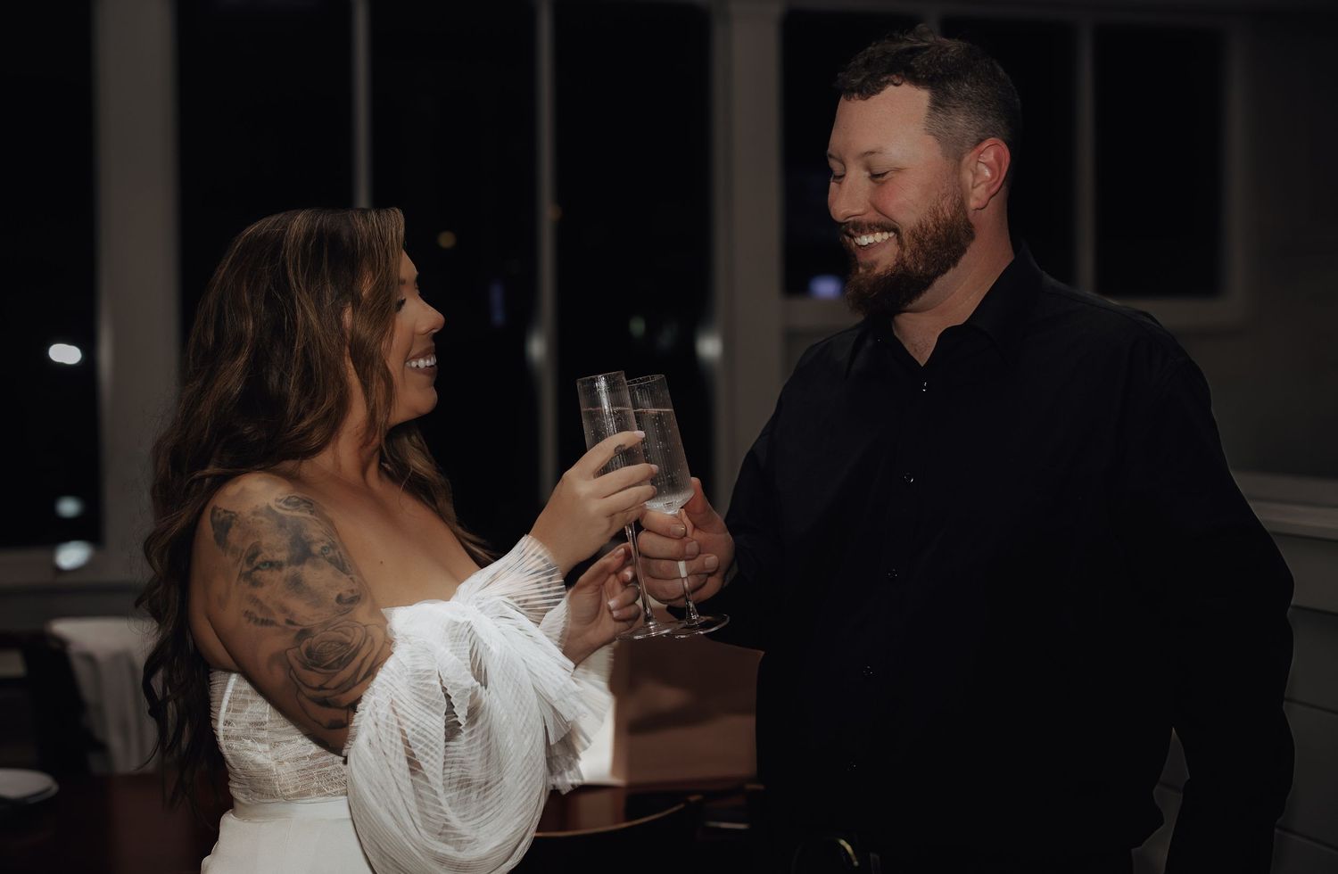 A couple dances together in a dimly lit room during what appears to be a wedding celebration.