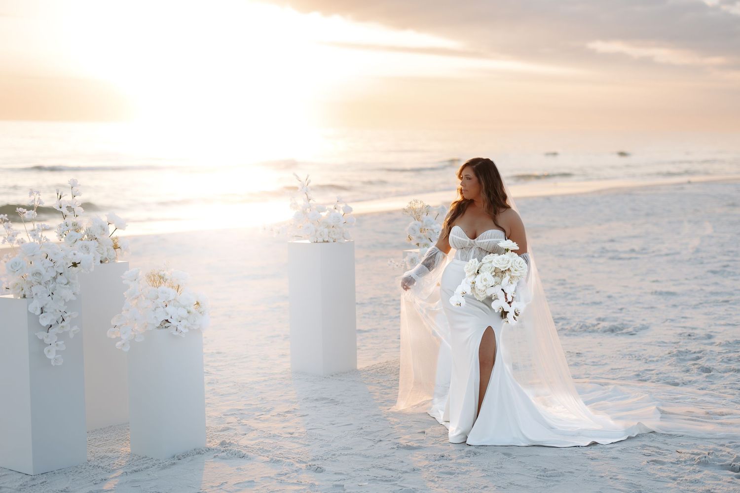 A bride in a flowing white dress stands on a sandy beach at sunset with white floral arrangements and ocean waves.
The Vinoy Resort & Golf