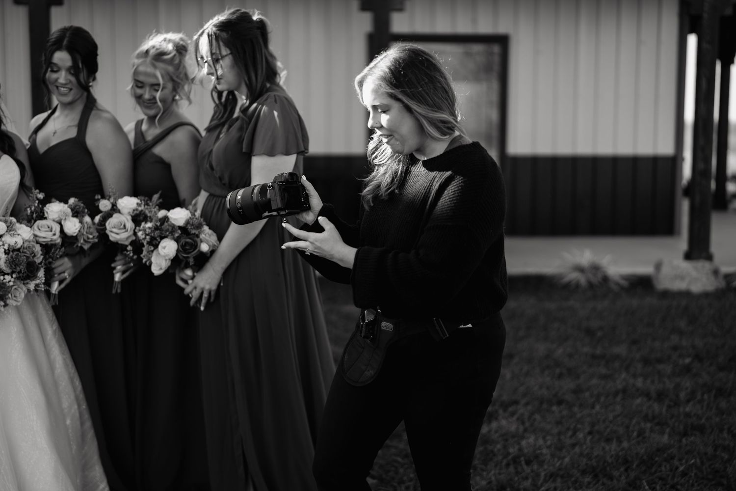 A group of bridesmaids in navy blue dresses react emotionally during an outdoor wedding ceremony.