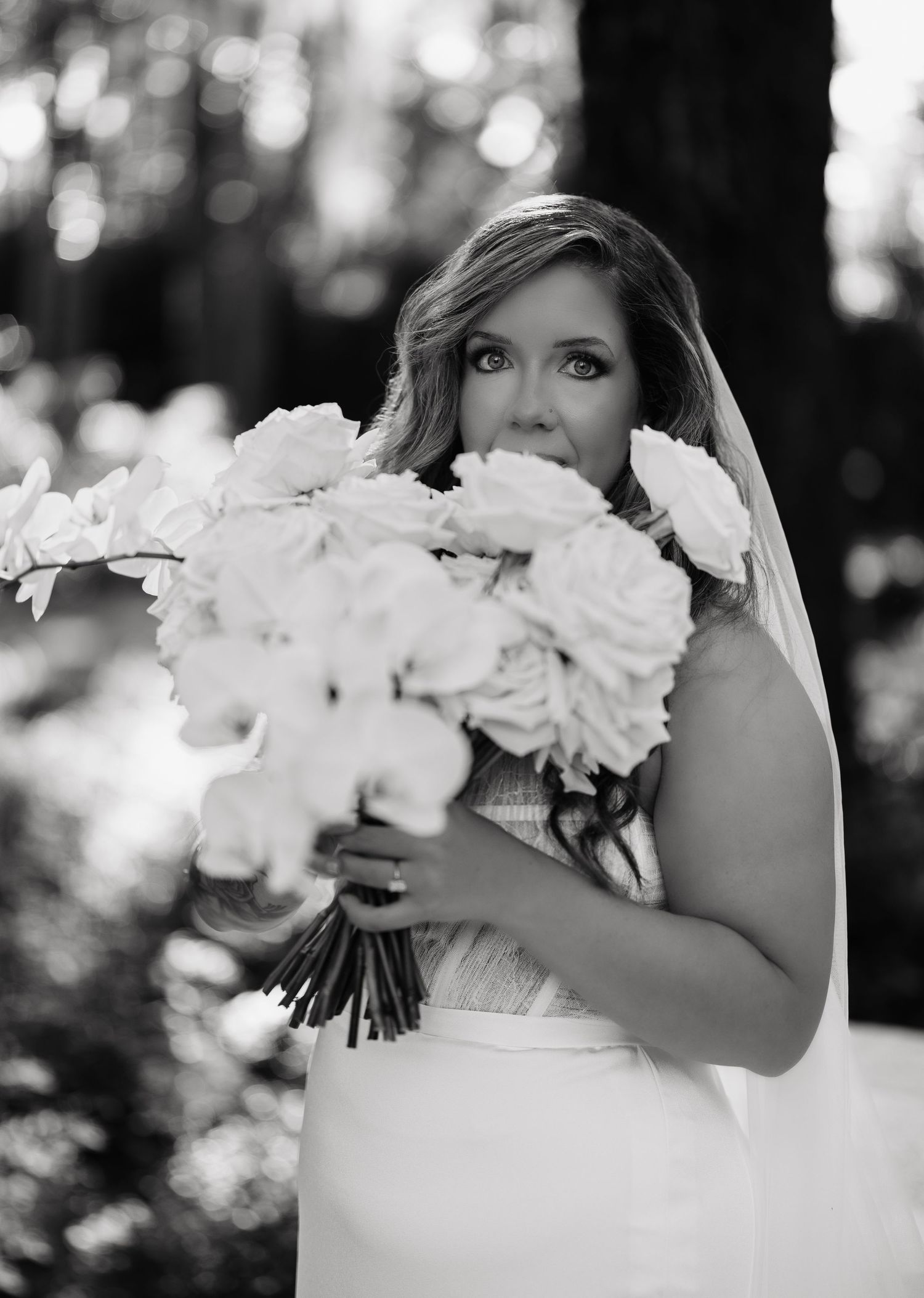 Black and white wedding photograph showing a white bouquet of roses and flowers against a softly blurred background.