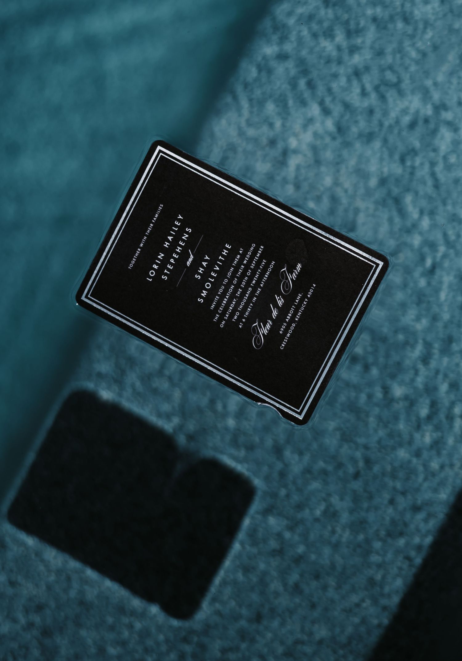 Black business card shown at different angles on a blue textured surface creating a dynamic composition.
