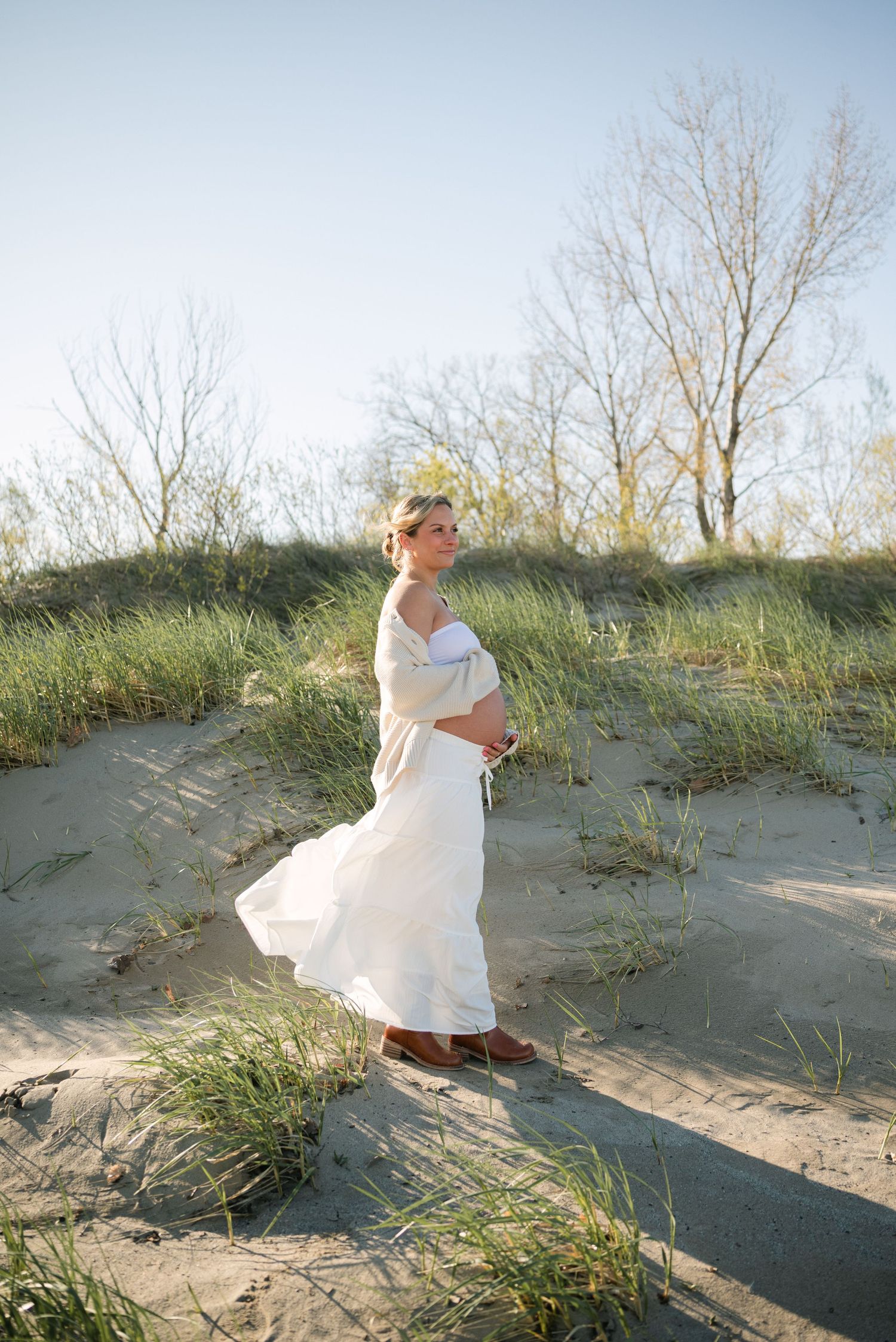 An expecting mother looks out toward the water at Woodlawn Beach State Park while her skirt blows in the wind