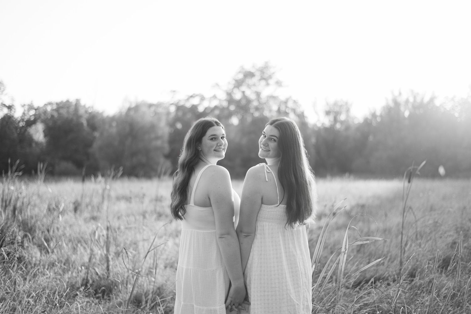 Twin brunette sisters smiling in a field