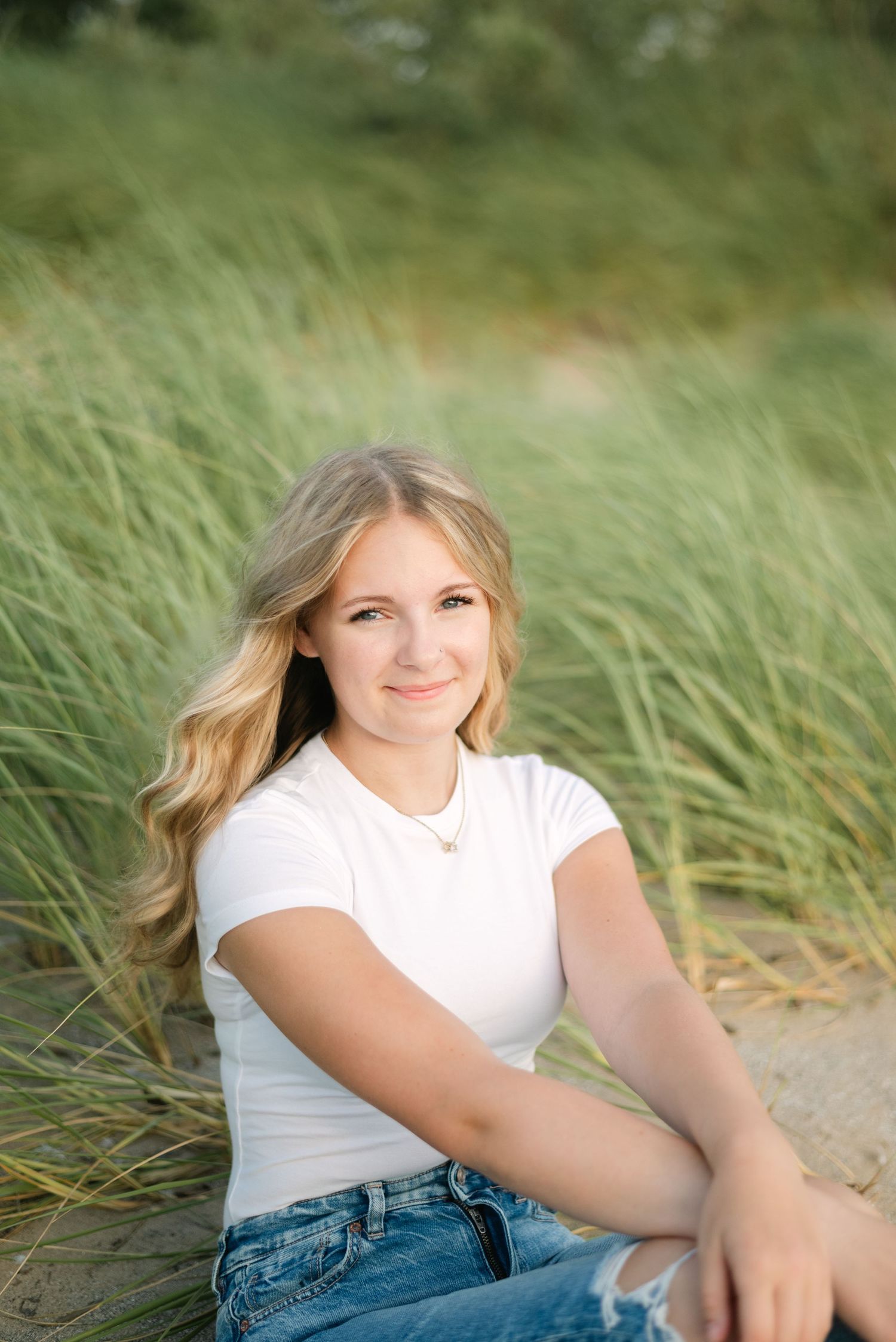 Blonde girl sitting in beach grass smiling