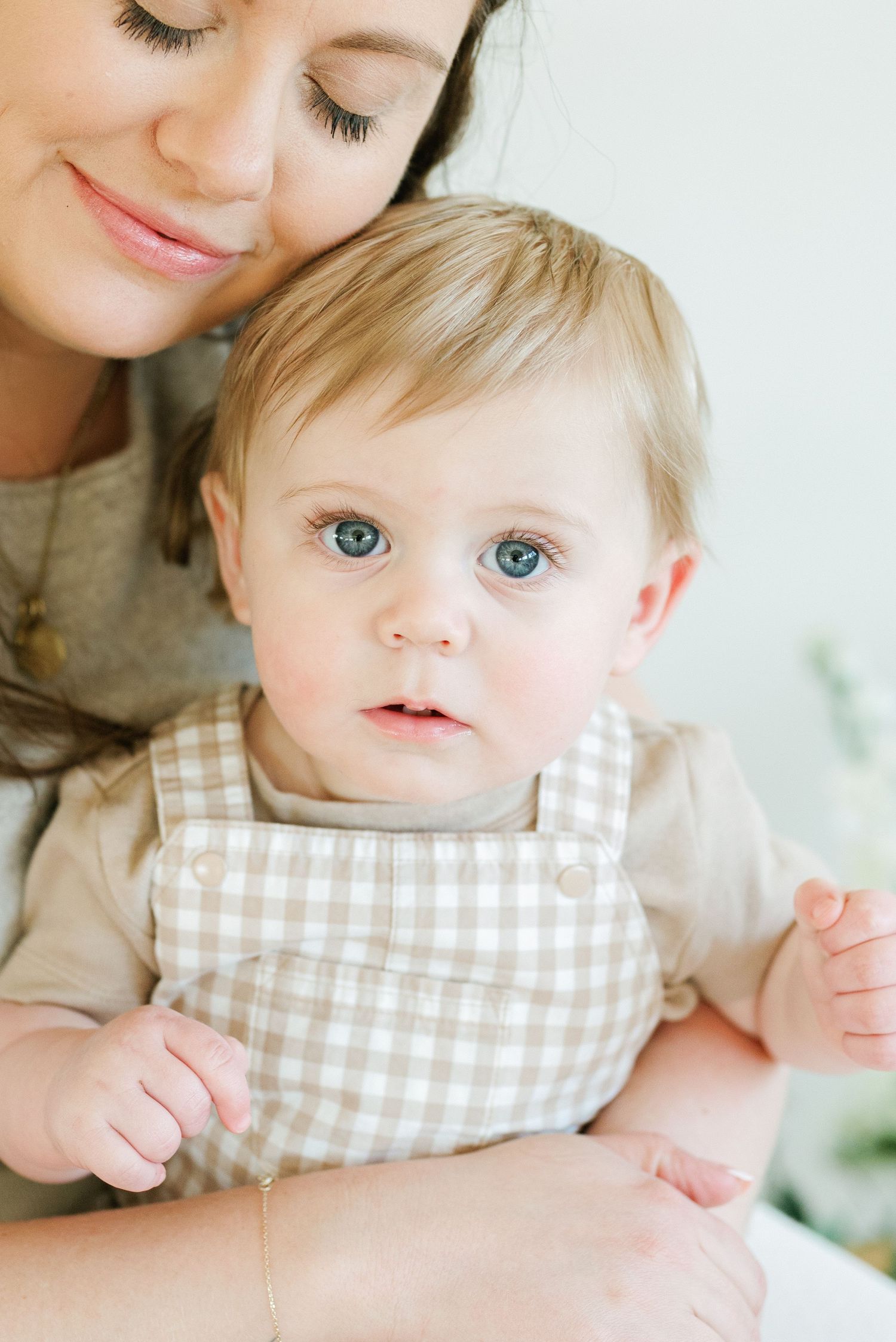 Mom rests her head, smiling, onto her son; his beautiful eyes highlight his sweet expression