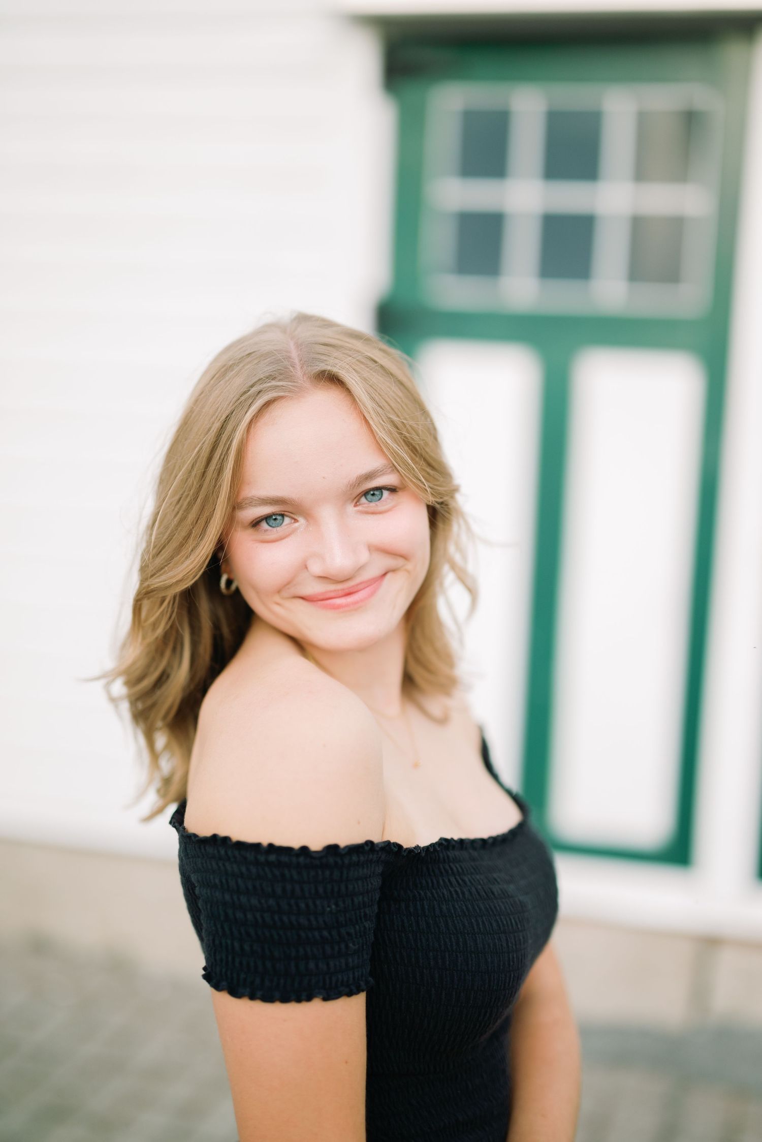 Blonde girl smiling in front of a white barn background