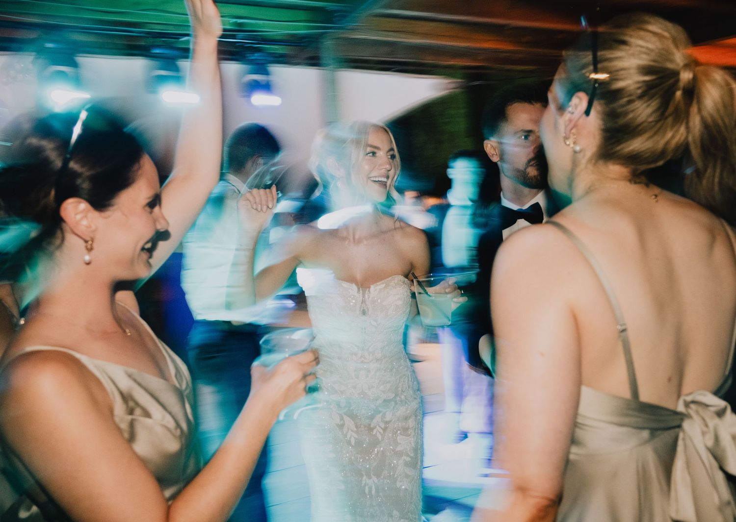 Wedding reception dance floor with colorful lights and celebrating guests.