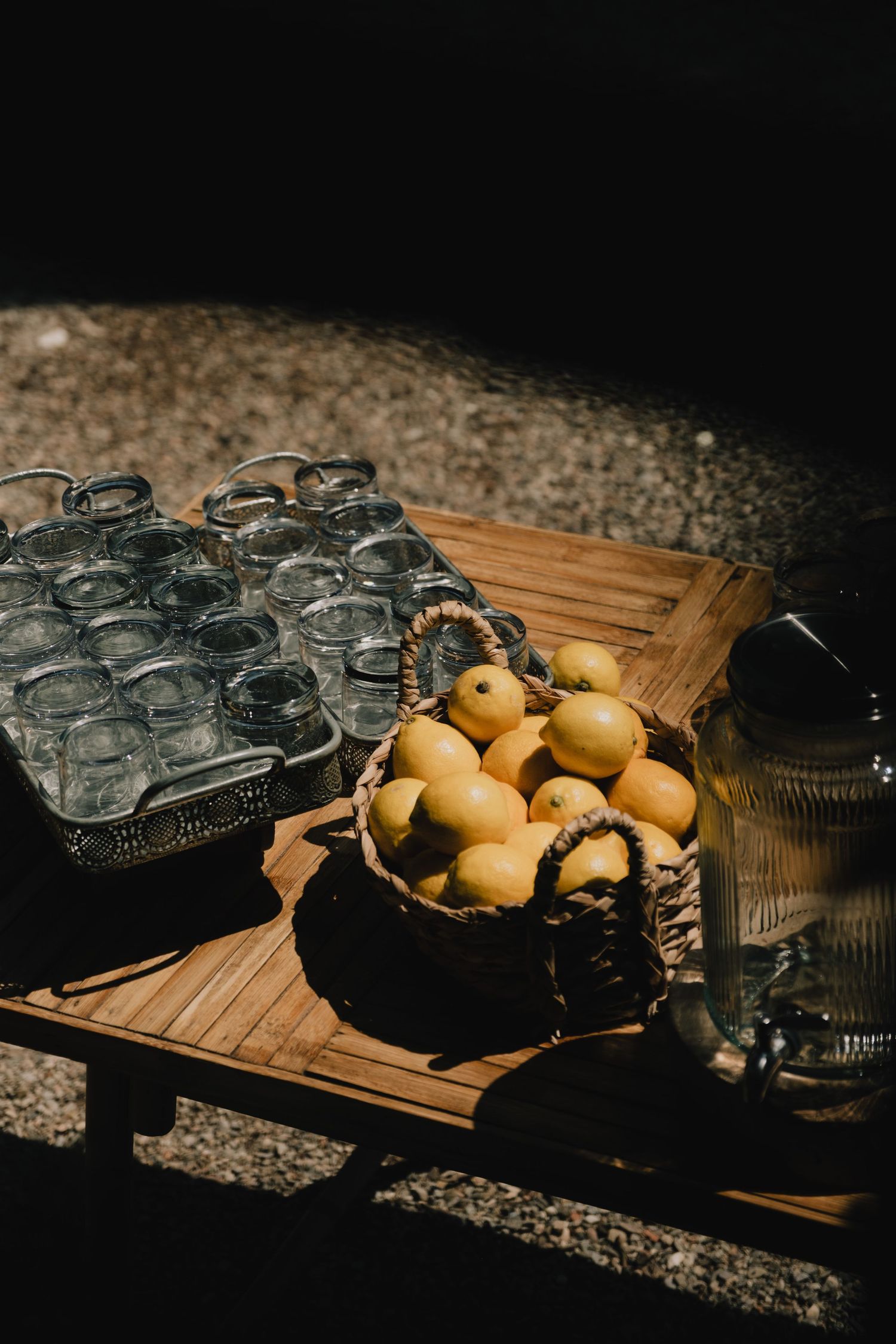 Mason jars and fresh lemons arranged on a wooden serving tray in dramatic lighting.