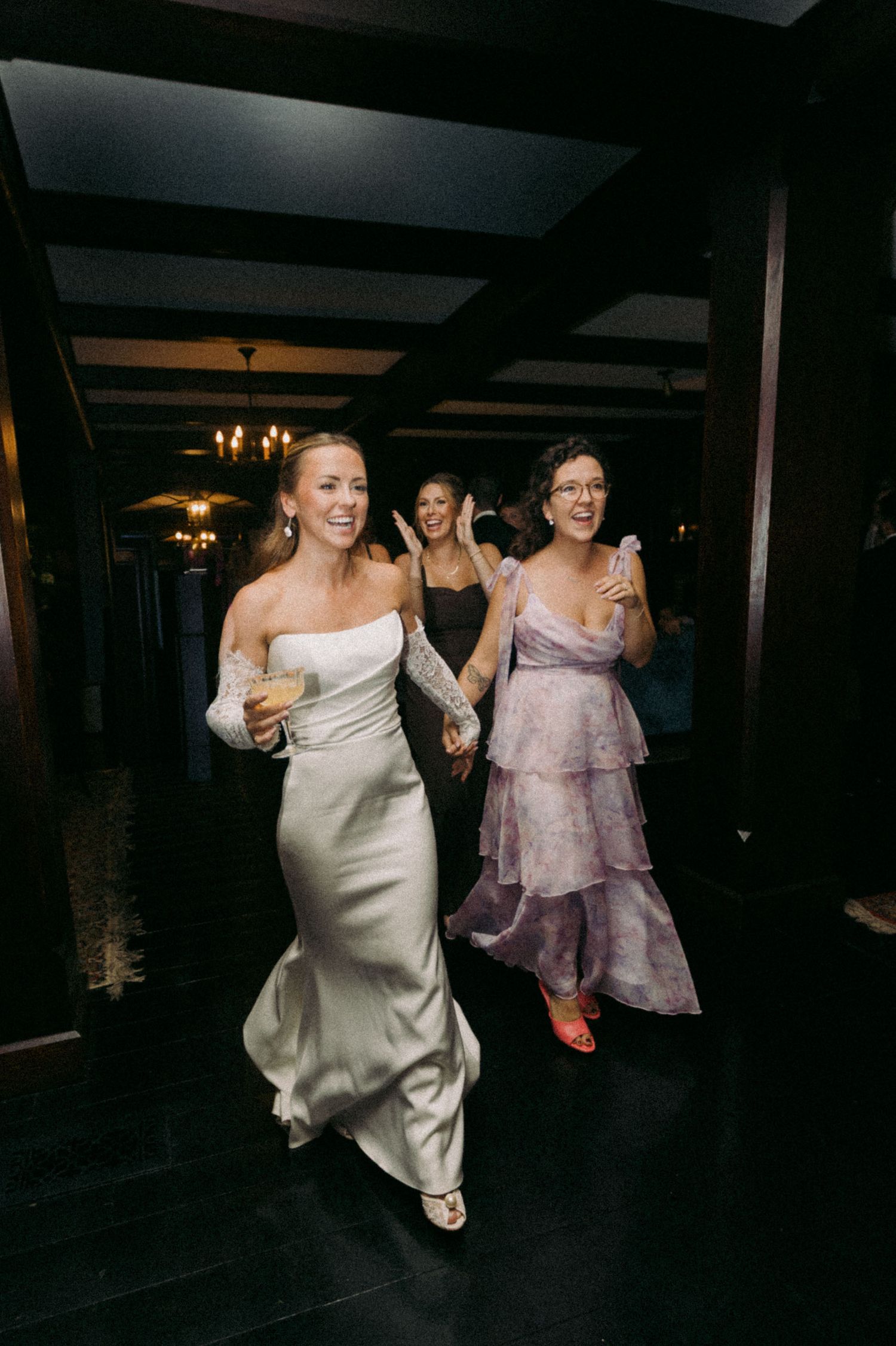 Two people in formal attire dance and enjoy themselves at a dimly lit reception venue.