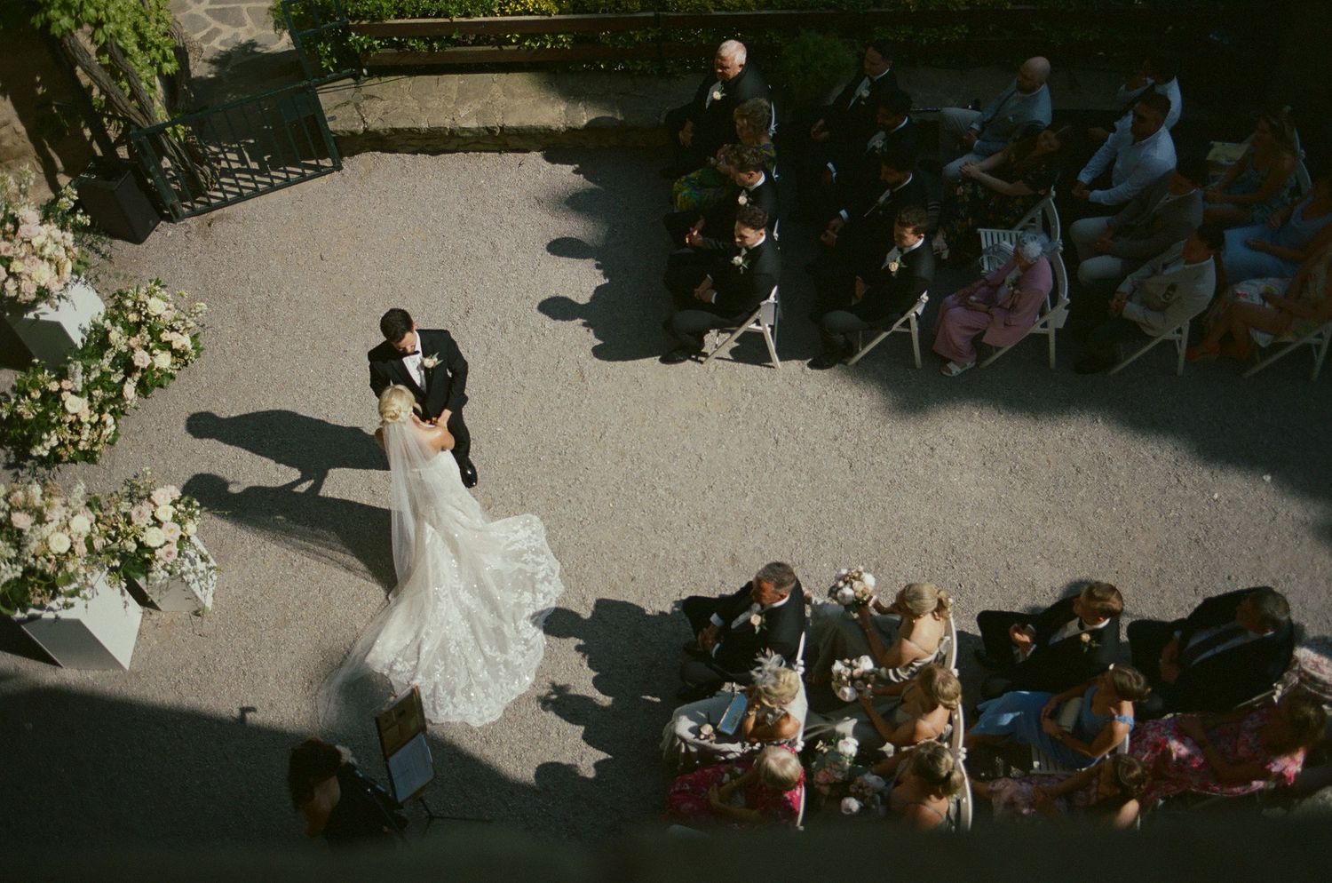 Aerial view of wedding guests seated in rows at an outdoor ceremony.