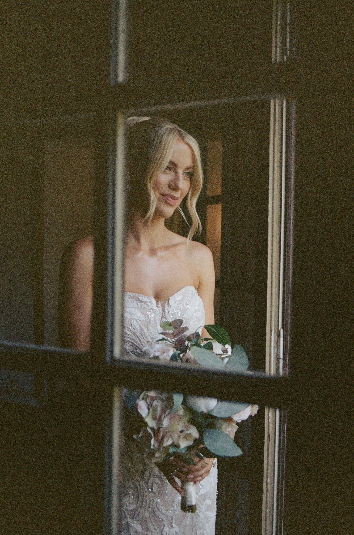 A wedding dress seen through a window pane with delicate floral details.