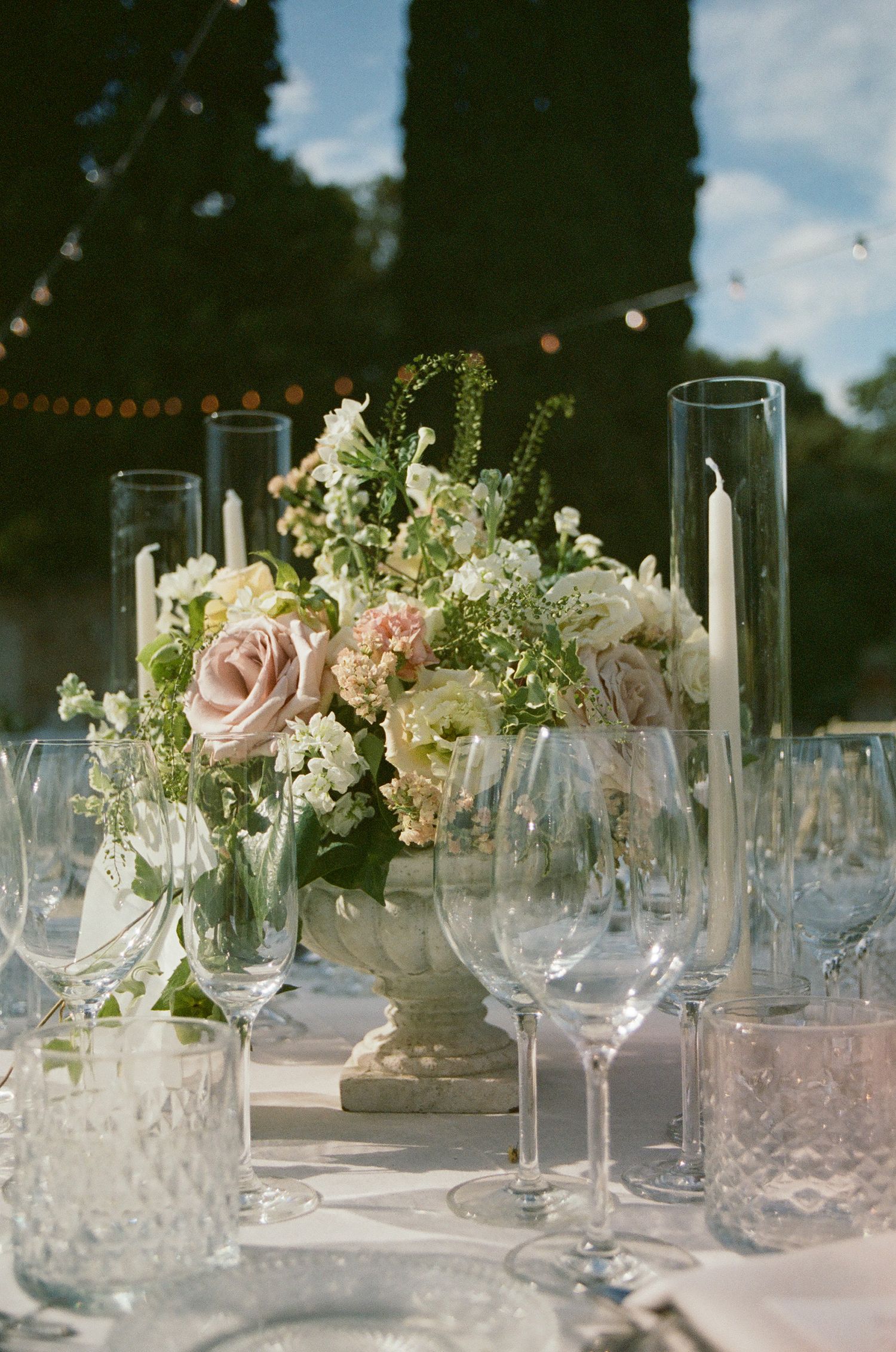Elegant table setting with pink roses, candles and crystal glassware at a wedding reception.