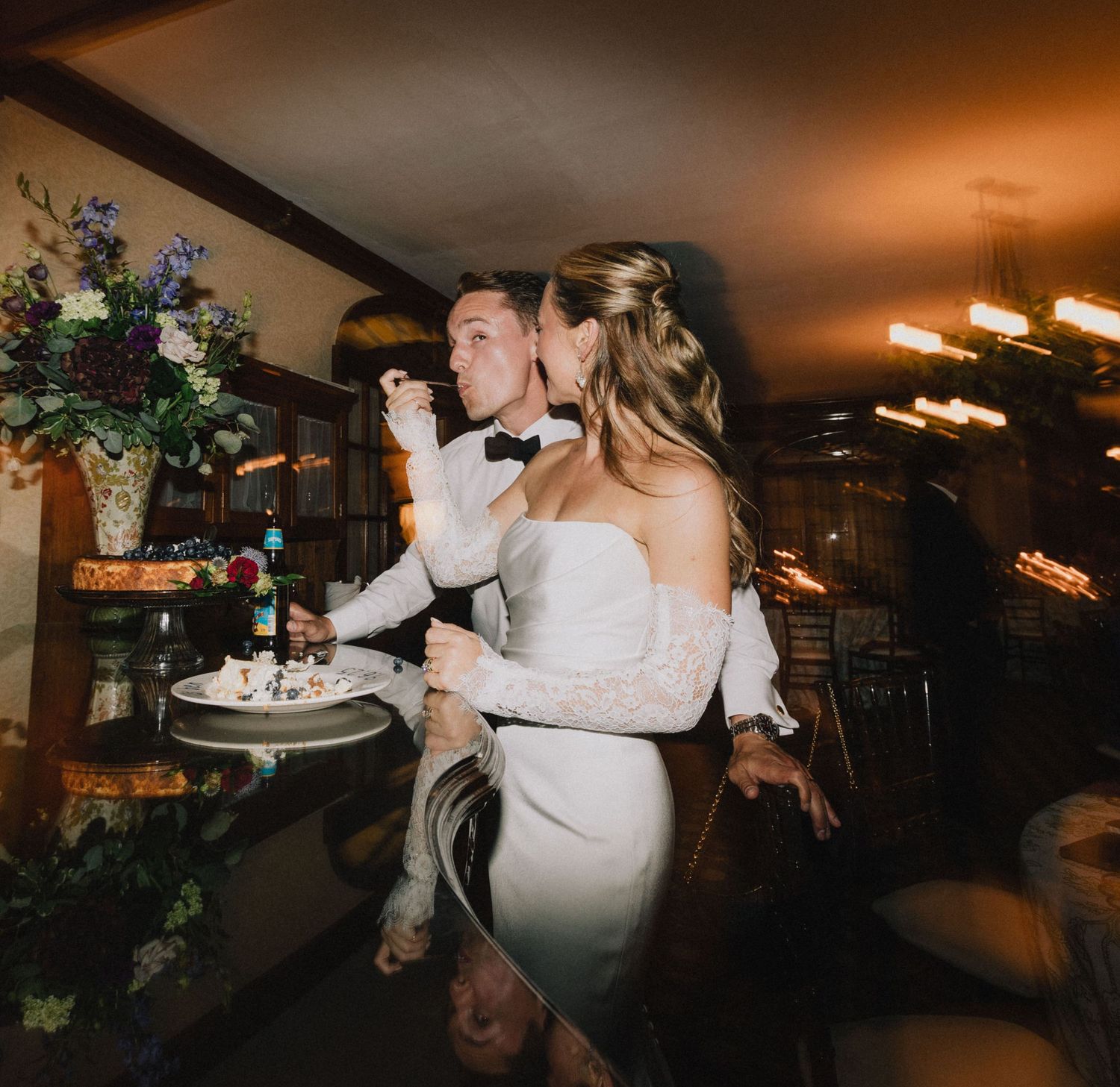 Silhouettes of a bride and groom dancing during their first dance in a dimly lit reception venue.