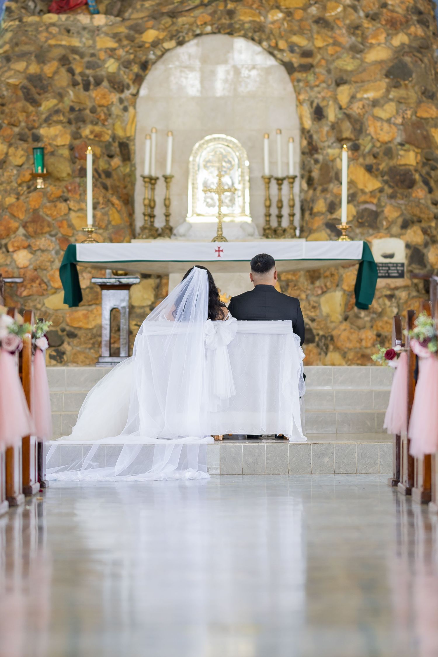 Wedding chapel interior with stone walls, white altar decorations and rows of chairs.