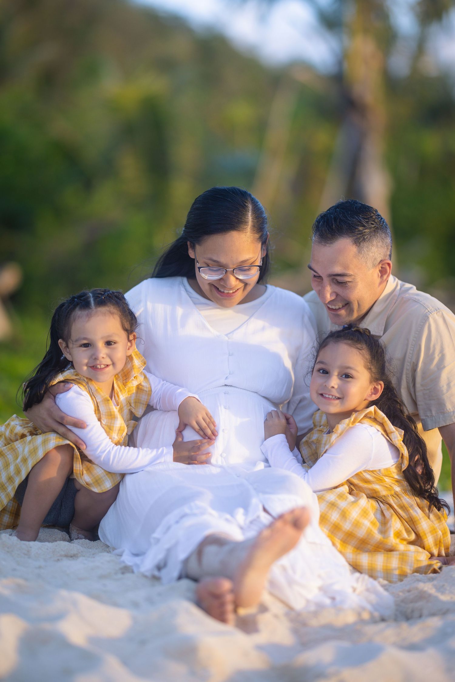 Family members lying together on white sand beach during golden hour.