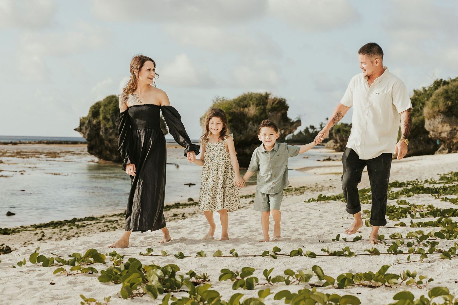 Family walking together along a rocky beach shore during cloudy weather.