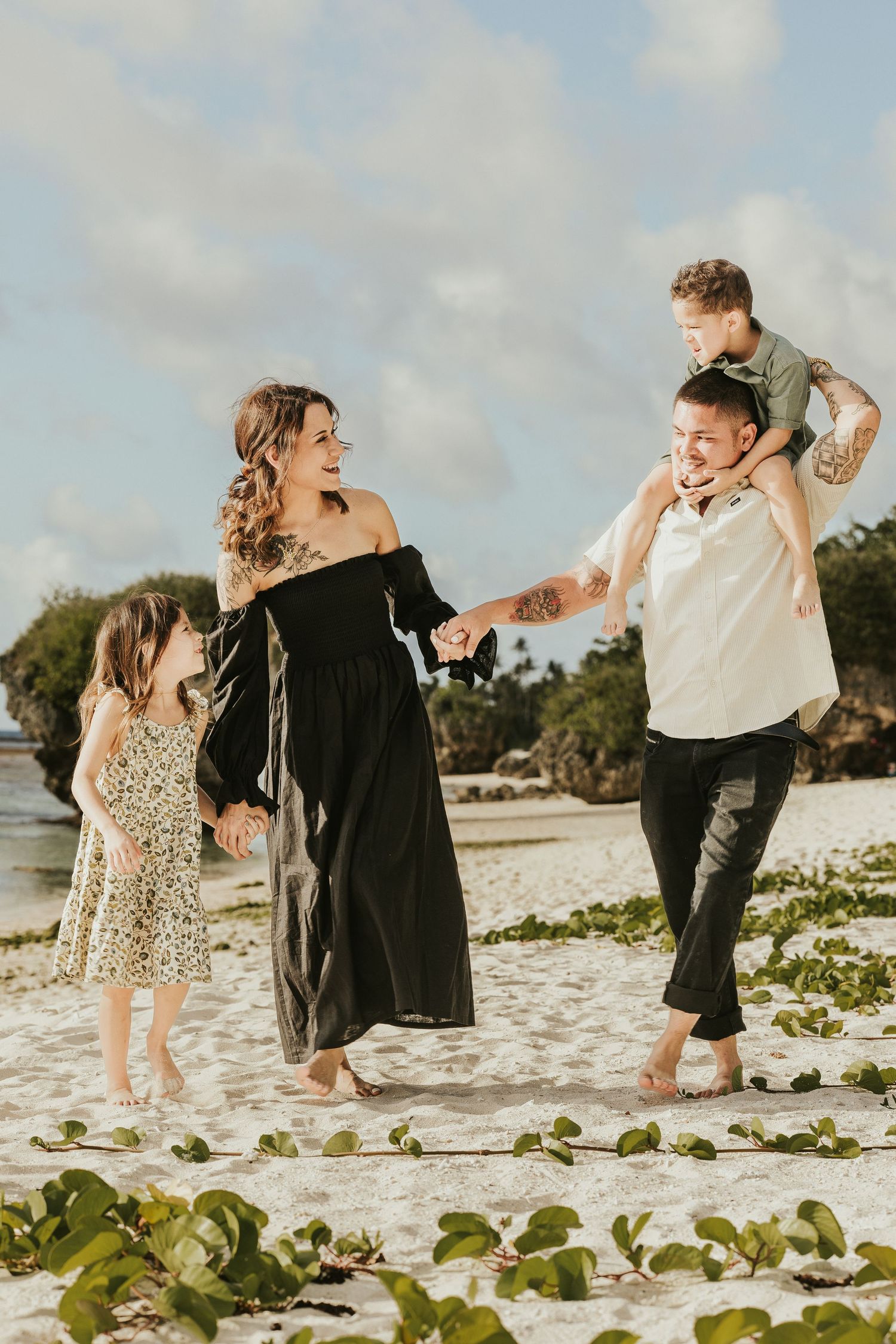 Family shares joyful moments together while playing on a sandy tropical beach.
