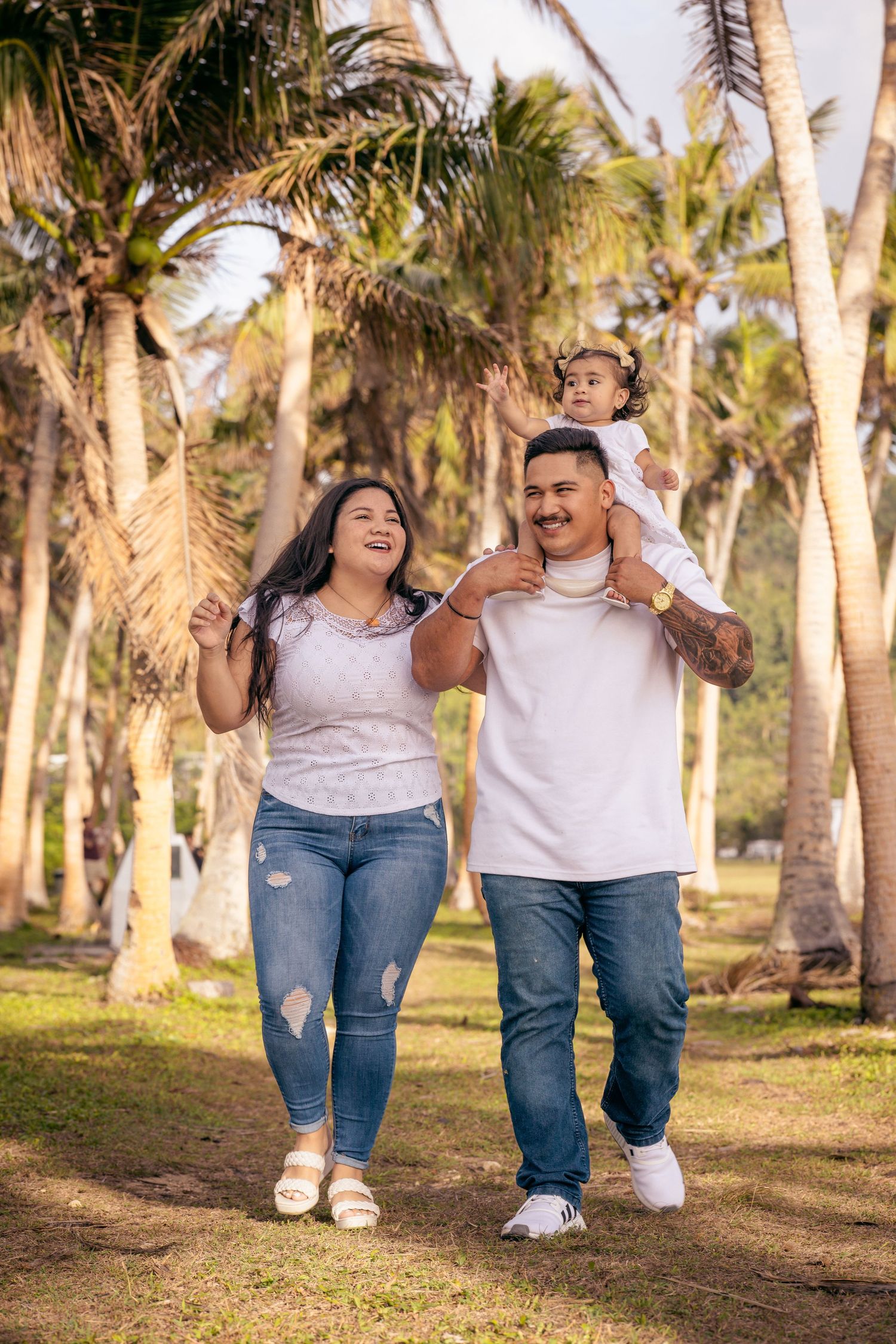 Family enjoying a walk through a scenic palm grove on a sunny day.
