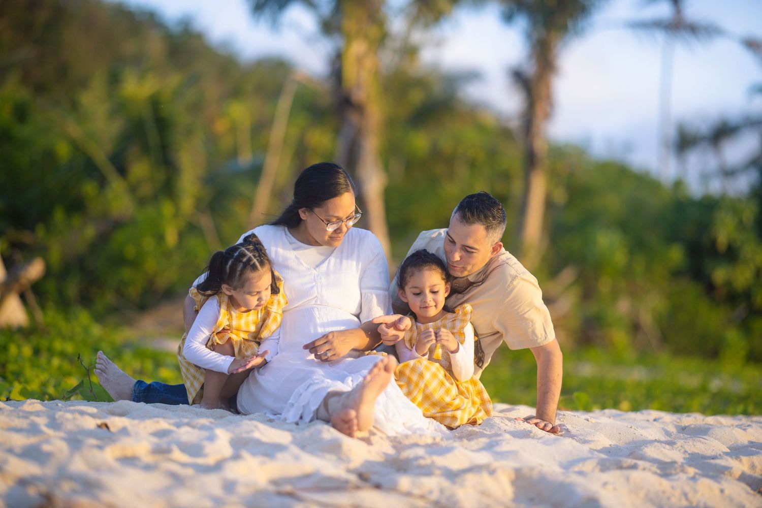 Family sharing intimate moments while relaxing on tropical beach sand.