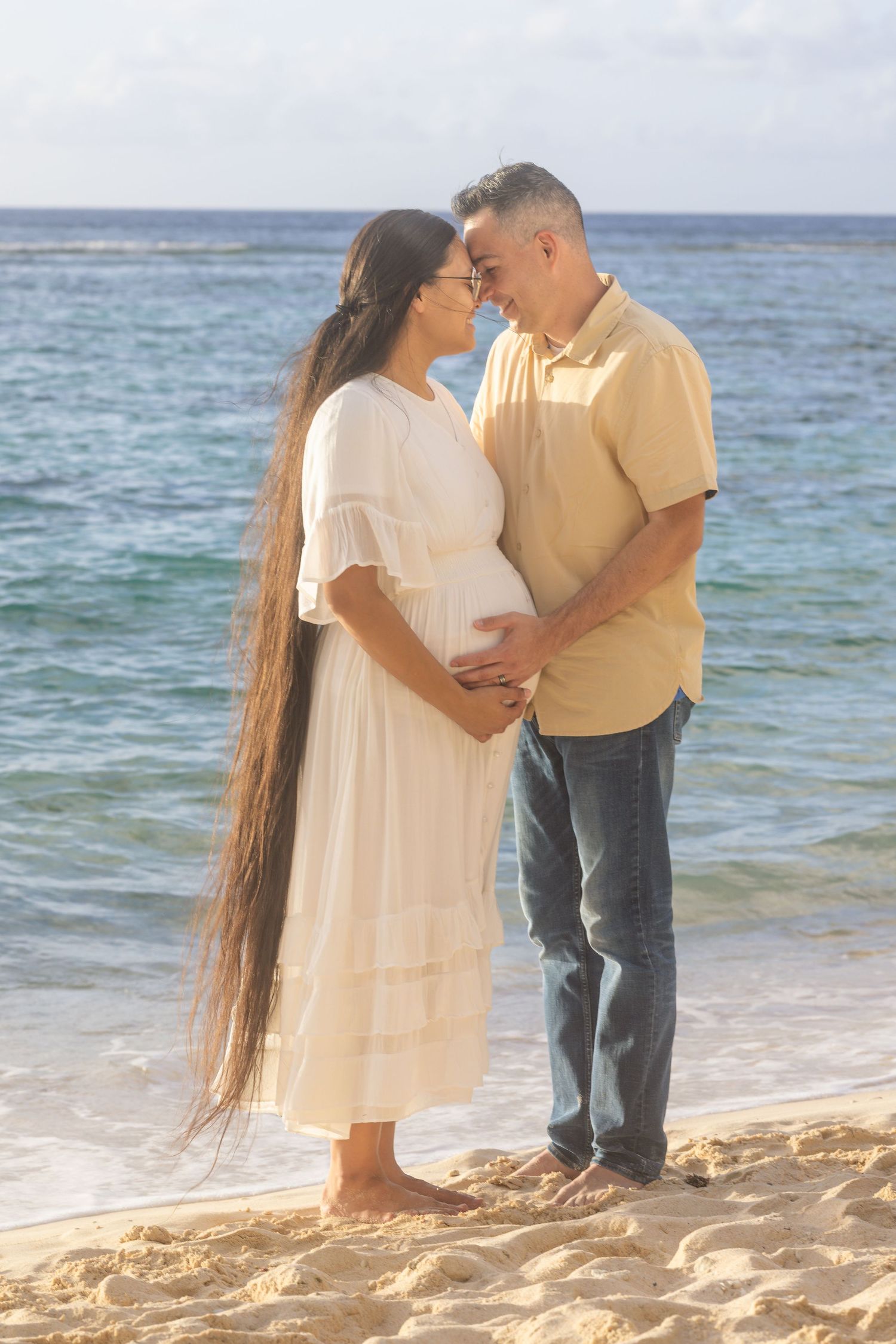 Intimate couple moment captured on a beach with waves and soft lighting.